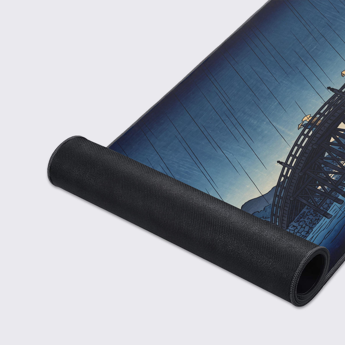 Mat partly rolled up showing its black non-slip rubber underside and printed rainy blue sky and arched bridge