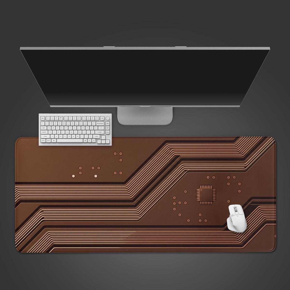 Brown circuit board desk mat with copper traces and a microchip, seen from above with a white keyboard, mouse and monitor