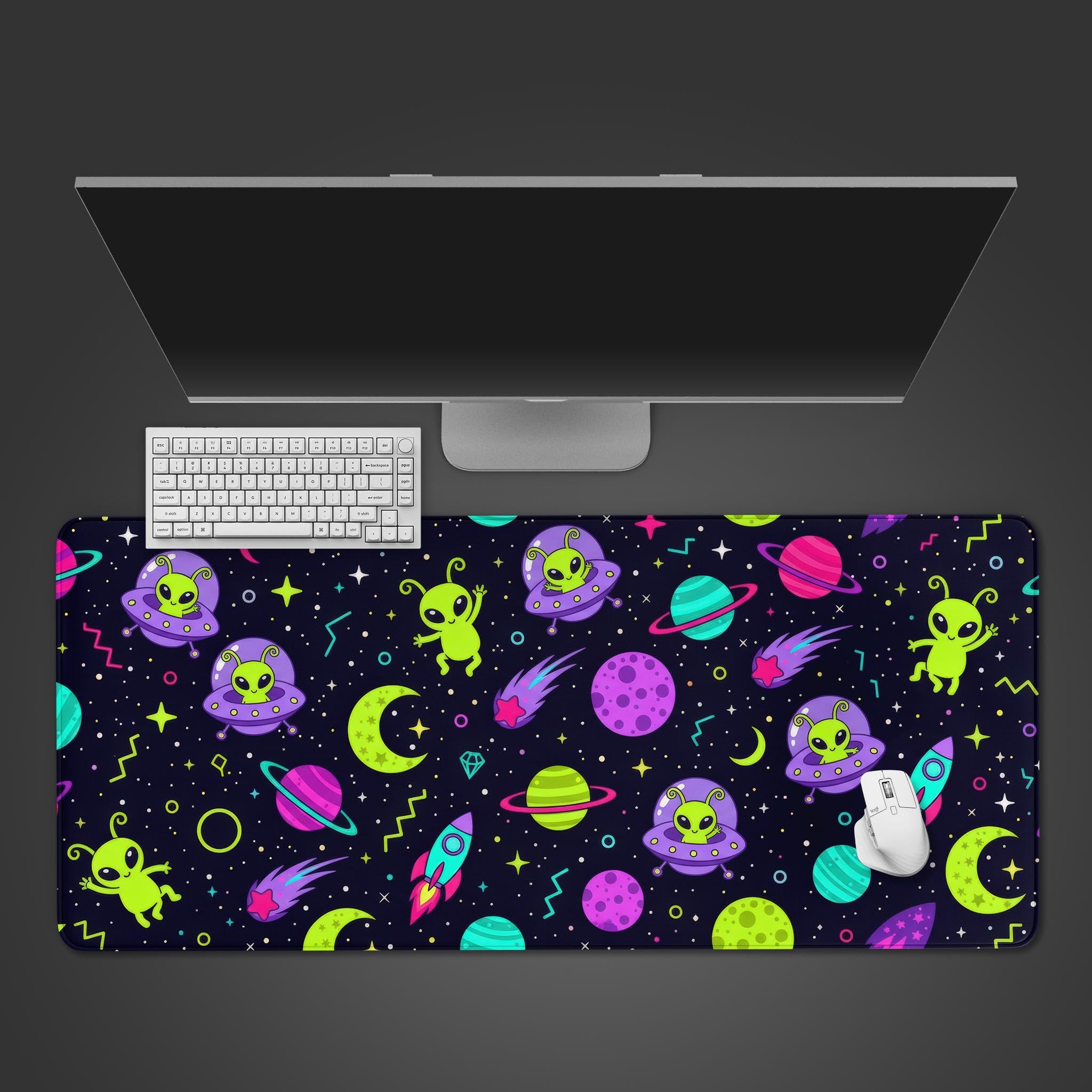 Cosmic Critters desk mat featuring cute lime-green aliens and purple UFOs, shown from a top-down view on a desk with a keyboard and mouse. - Epic Design Pads