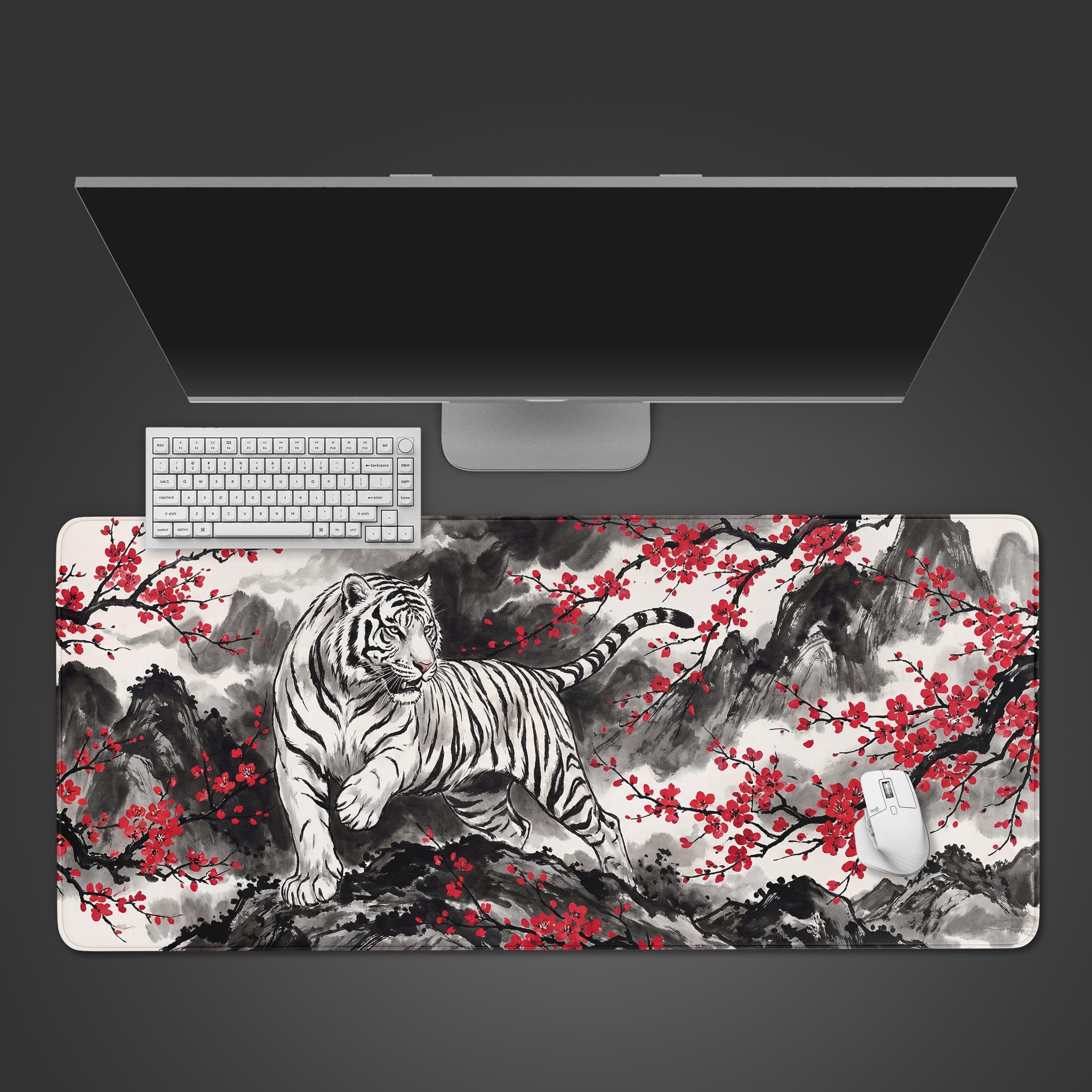 Top-down view of the Crimson Tiger gaming desk mat featuring an ink wash tiger and red blossoms, shown with a white keyboard, mouse, and sleek monitor on a dark surface. - Epic Design Pads & Mousepads