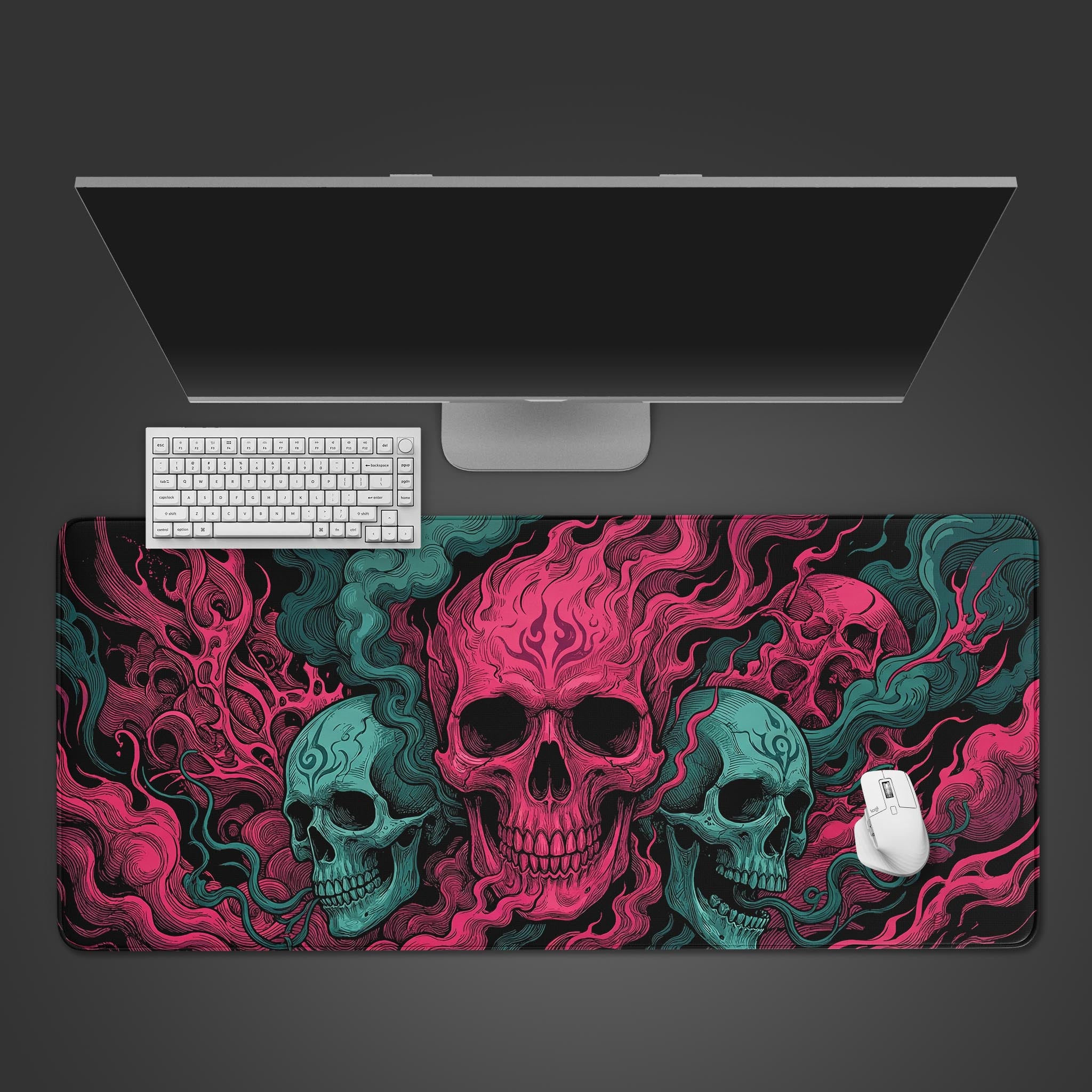 Top-down view of the Crimson Trinity skulls gaming desk mat, shown with a white keyboard, mouse, and a large monitor on a dark grey surface. - Epic Design Pads & Mousepads