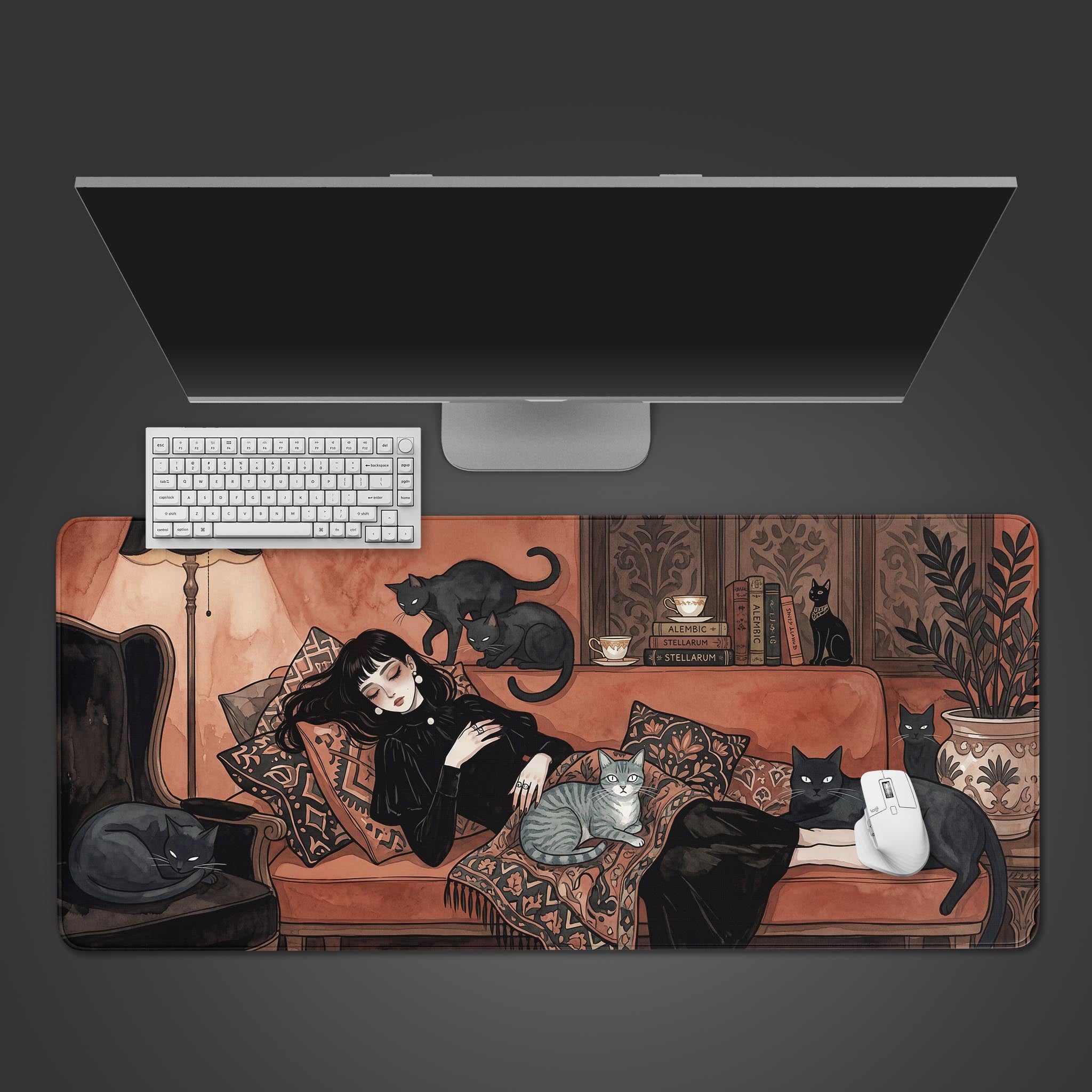 The 'Familiar Rest' gaming desk mat viewed from the top, displayed with a white keyboard, a white mouse, and a sleek monitor, showcasing the cozy cat and book-themed artwork. - Epic Design Pads & Mousepads
