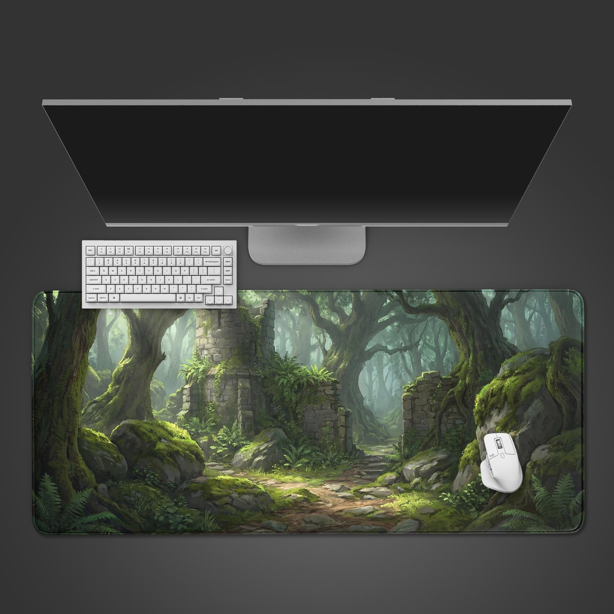 Top-down view of the Forgotten Path Gaming Desk Mat, showing the fantasy forest ruins design alongside a white keyboard, mouse, and a large monitor on a dark surface. - Epic Design Pads & Mousepads