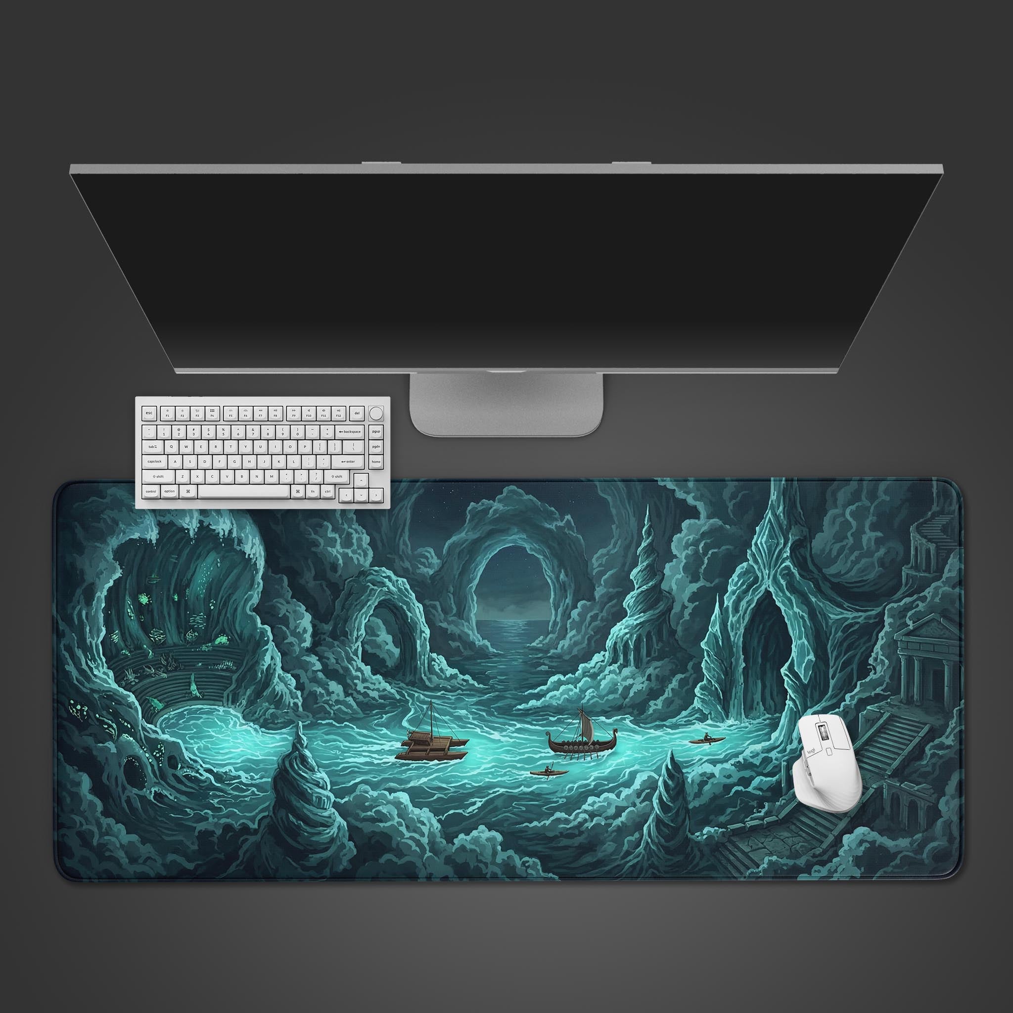 Top-down view of the Forgotten Realm gaming desk mat, showing the epic cave and sea design beneath a white keyboard, mouse, and monitor on a dark surface. - Epic Design Pads & Mousepads
