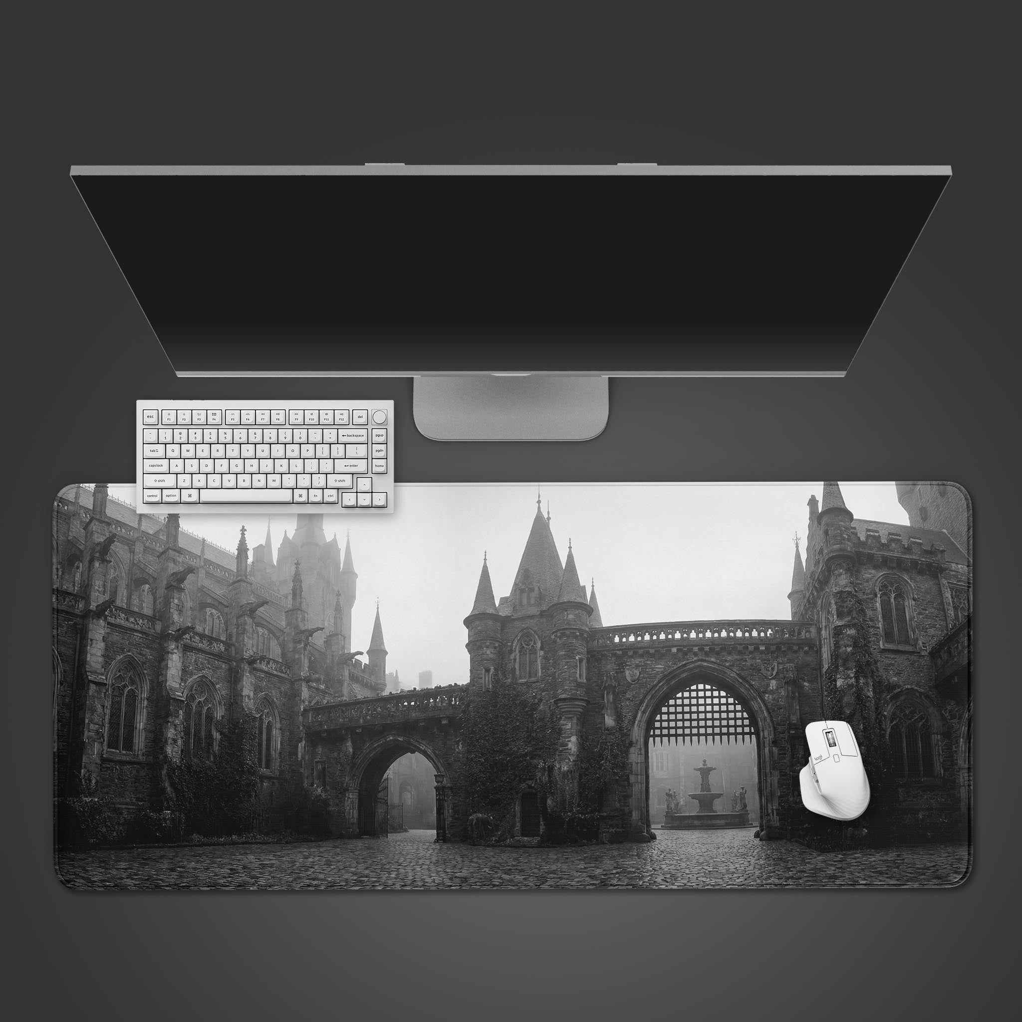 A top-down view of the Gothic Courtyard gaming desk mat, shown with a white keyboard and mouse on a dark background. The design features a monochrome castle scene. - Epic Design Pads & Mousepads