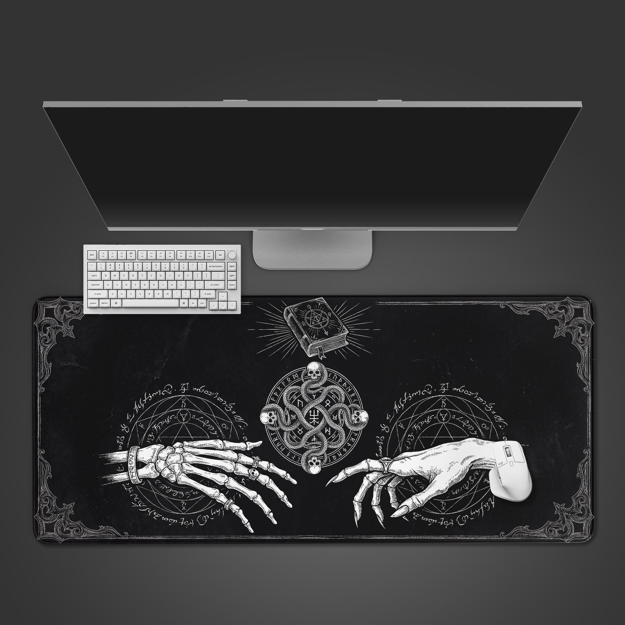 Top-down view of the Grimoire Bind gaming desk mat featuring an occult design, shown with a white keyboard and monitor on a dark surface. - Epic Design Pads & Mousepads