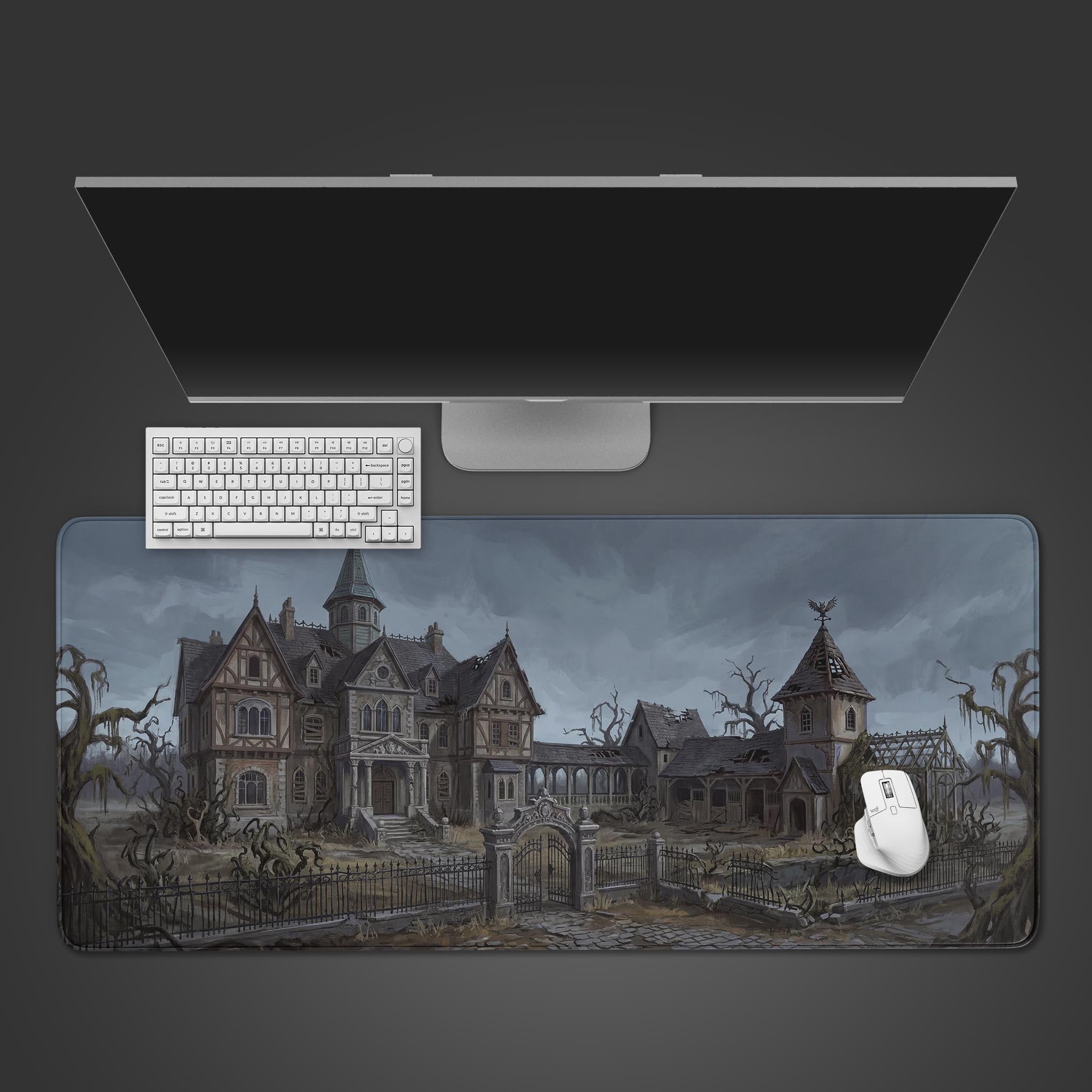 The Haunted Grounds gaming desk mat shown from above with a white keyboard and mouse, featuring its eerie gothic manor illustration. - Epic Design Pads & Mousepads