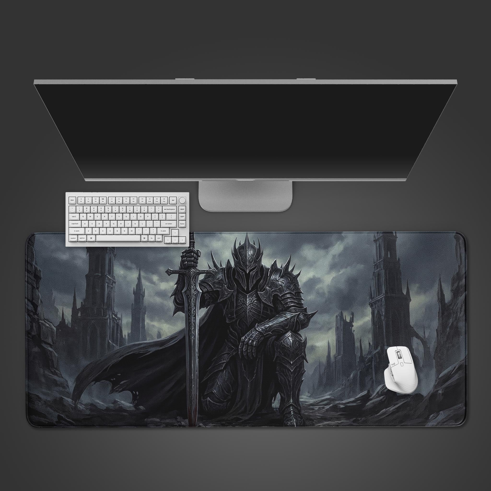 Top-down view of the Iron Oath gaming desk mat featuring a dark fantasy knight, shown with a white keyboard and mouse under a monitor on a gray surface. - Epic Design Pads & Mousepads