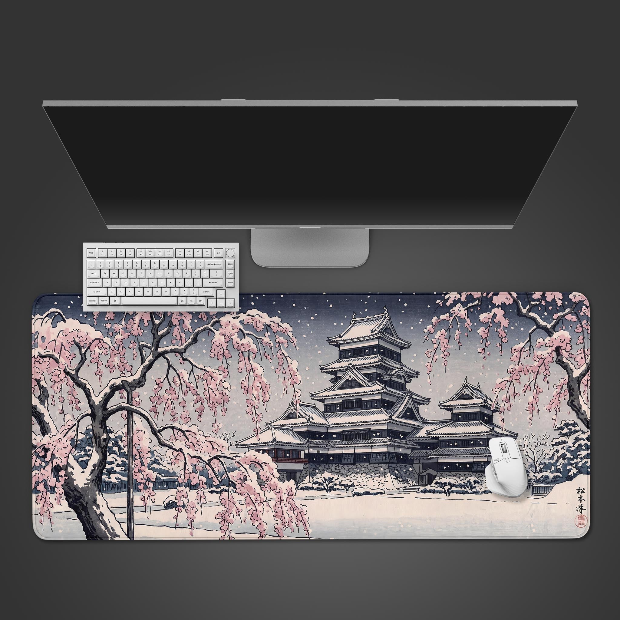 A desk mat featuring a traditional Japanese castle in winter, surrounded by snow-dusted pink cherry blossoms.