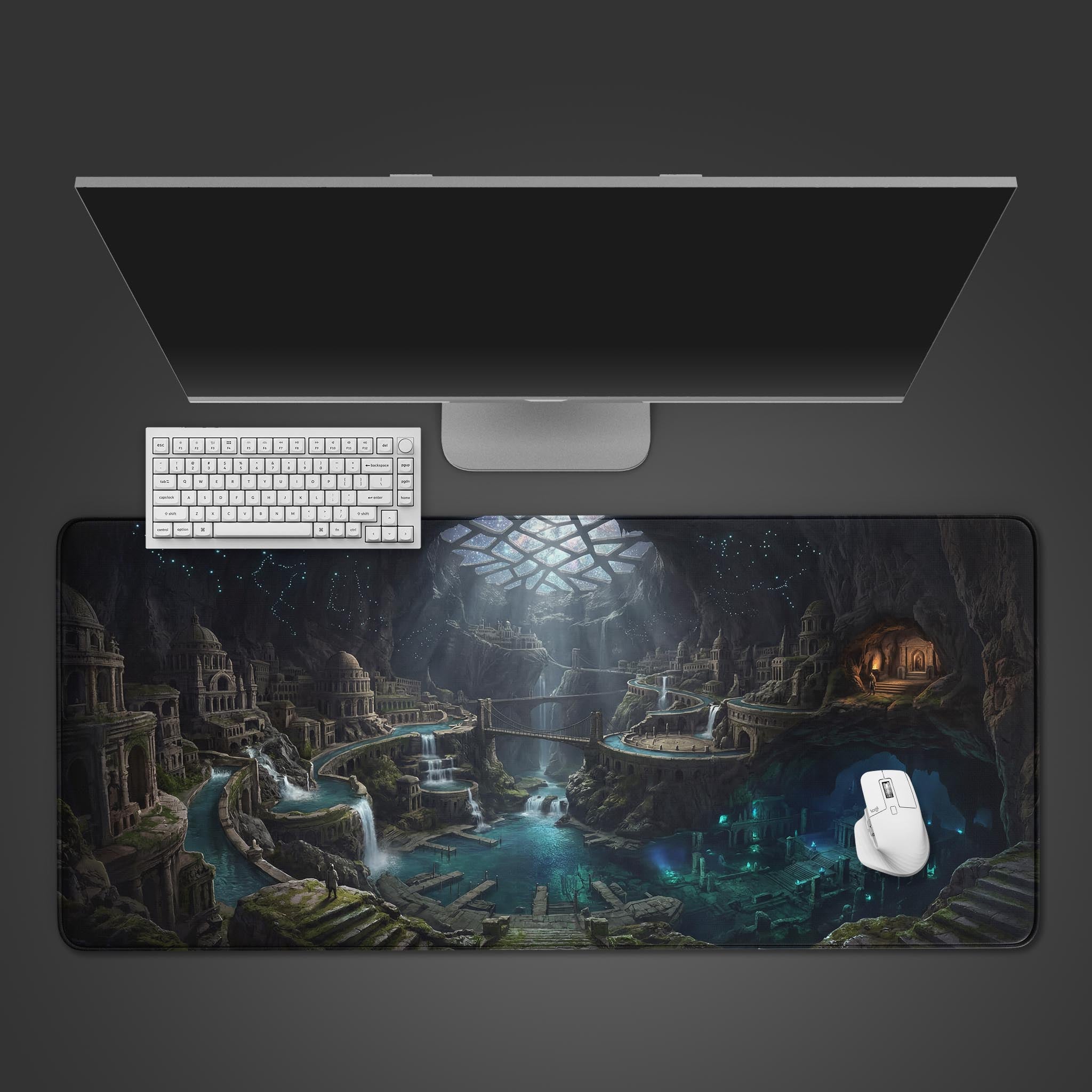 Top-down view of the Lost Cavern City gaming desk mat, showcasing its fantasy design with a white keyboard, mouse, and a large monitor on a dark background. - Epic Design Pads & Mousepads