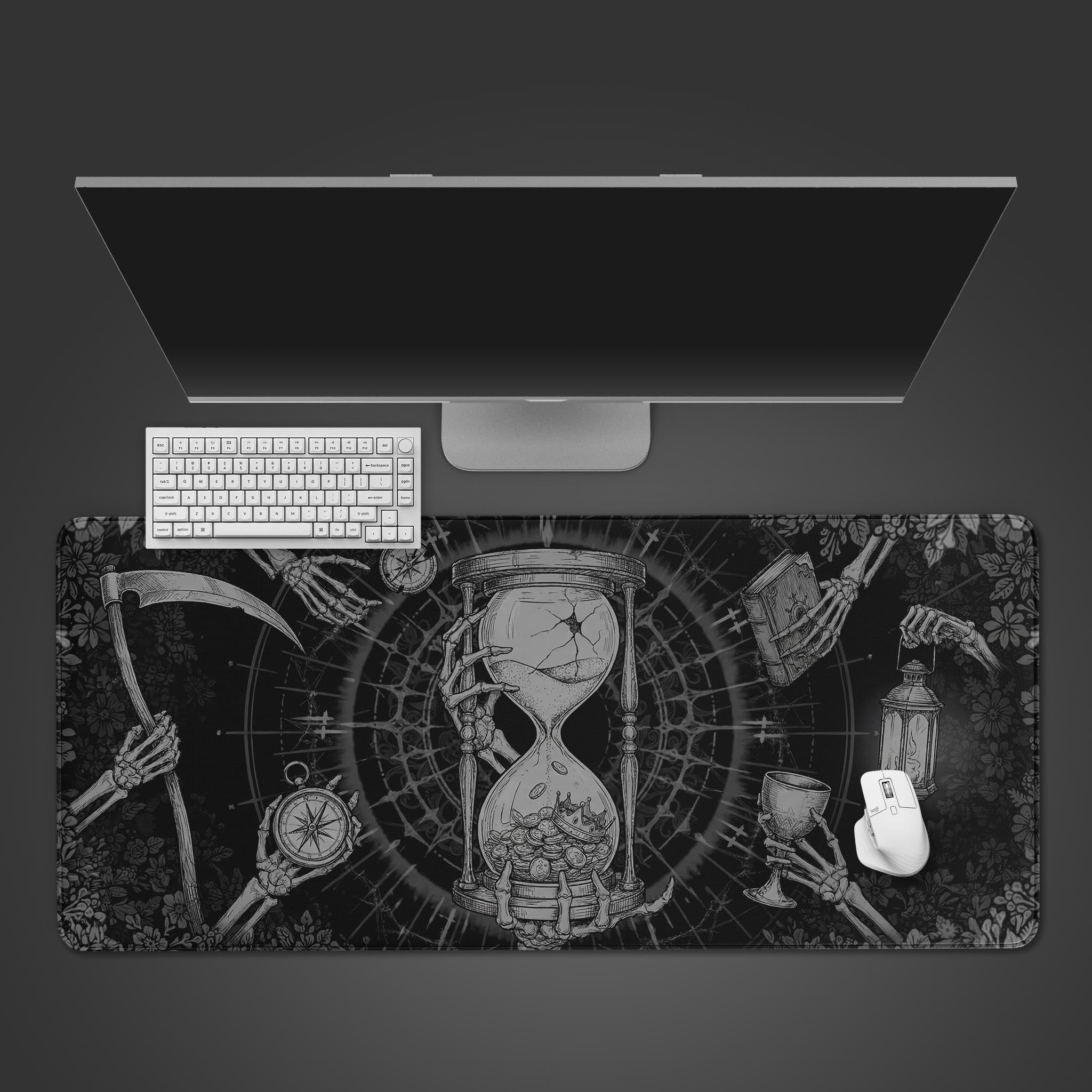 Top-down view of the Memento Mori gaming desk mat featuring a skeletal hourglass design, shown with a white keyboard, mouse, and a large monitor on a dark surface. - Epic Design Pads & Mousepads