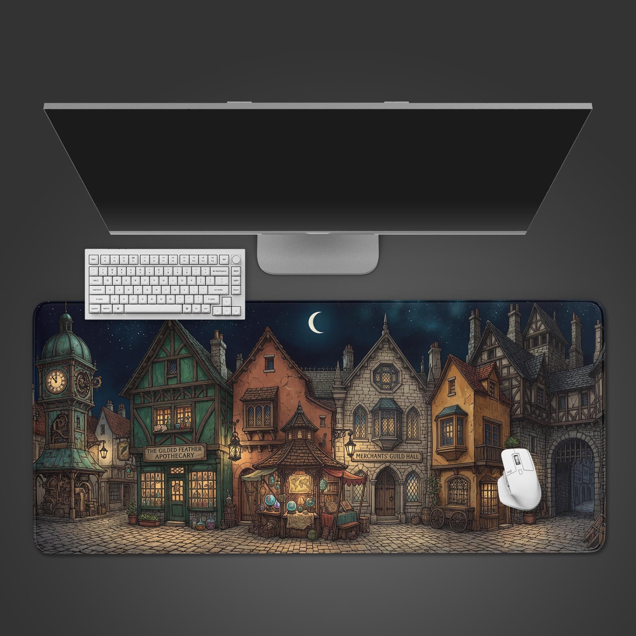 A top-down view of the Merchant's Row gaming desk mat showing a fantasy village scene. A white keyboard and mouse are placed on top, with a monitor above. - Epic Design Pads & Mousepads