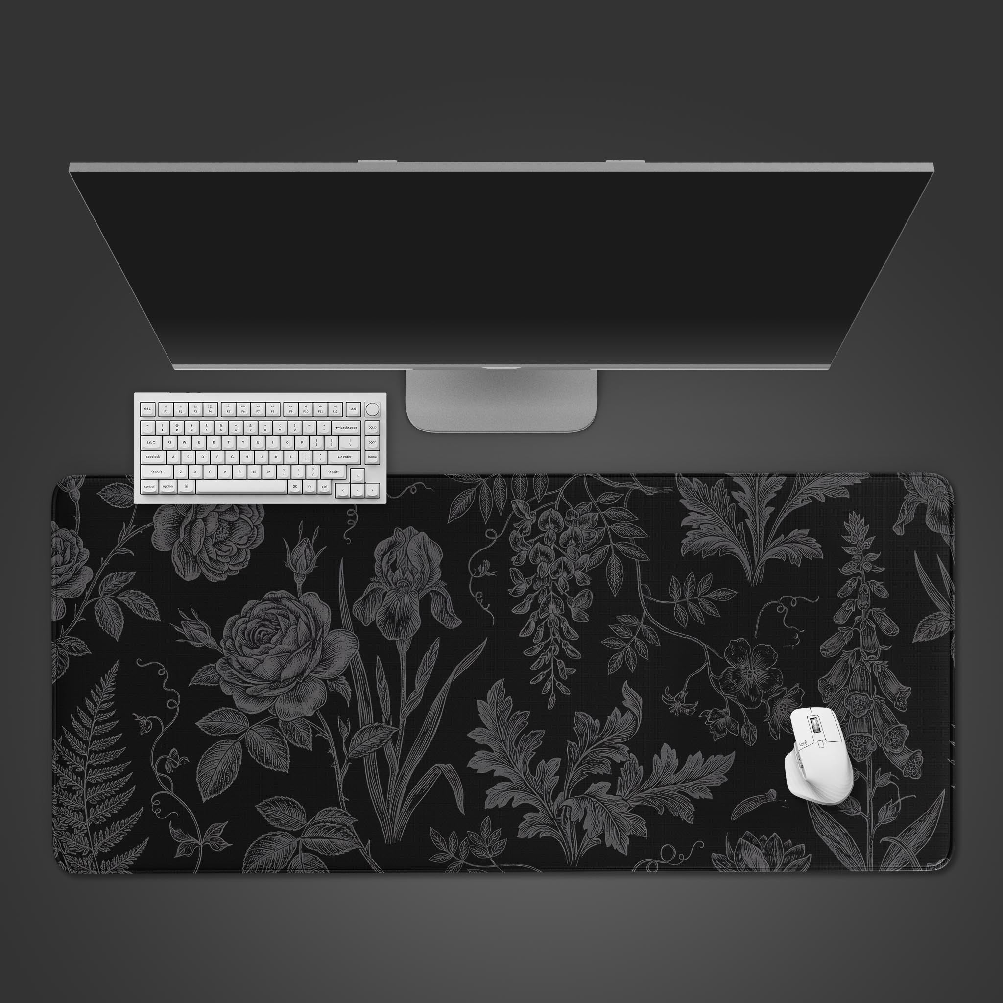 Top-down view of the Midnight Botany gaming desk mat, featuring a vintage floral design, with a white keyboard, mouse, and monitor arranged on a dark grey surface. - Epic Design Pads & Mousepads