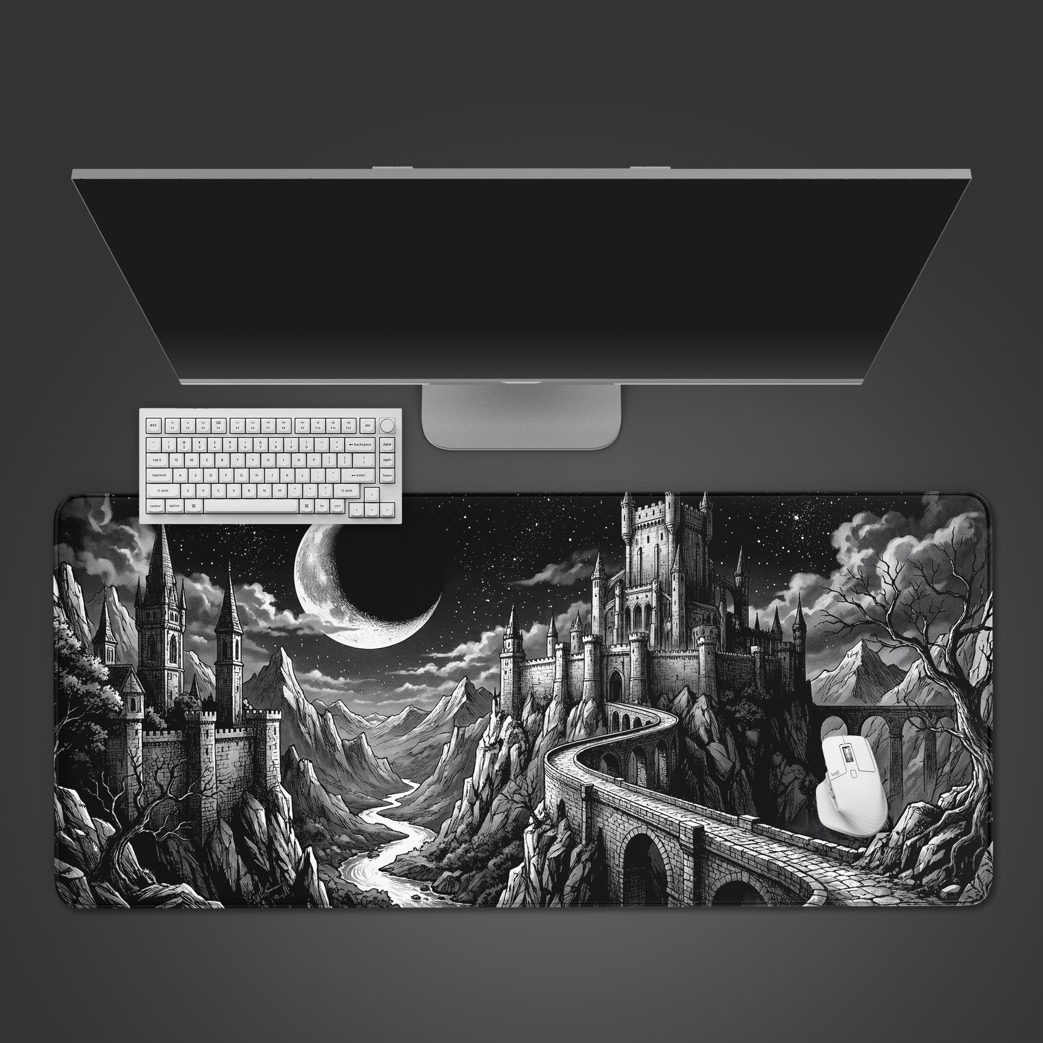 Top-down view of the Moonlit Bastion gaming desk mat, featuring a black and white castle landscape, with a white keyboard and mouse placed on top. - Epic Design Pads & Mousepads
