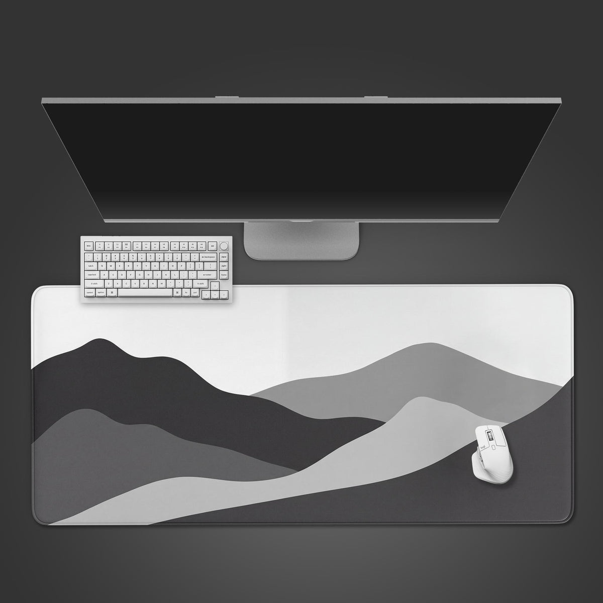 A minimalist desk mat featuring rolling mountain peaks in shades of grayscale, white, and black.