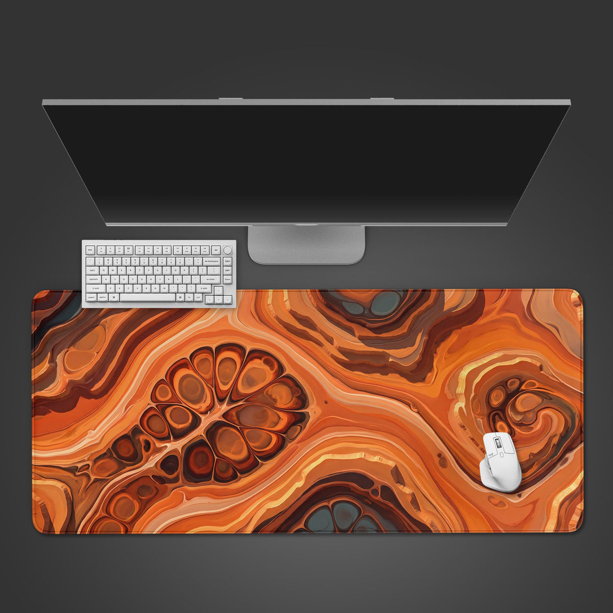 Top view of an orange fluid art abstract desk mat with rust and gray cells under a monitor, white keyboard and mouse.