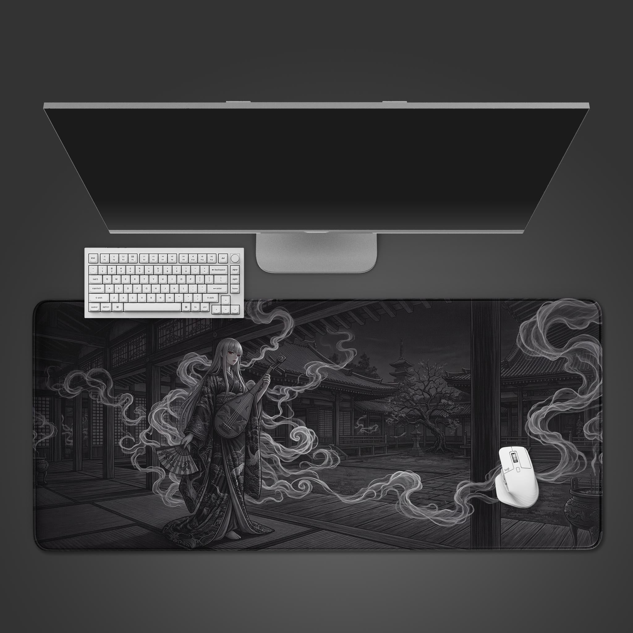 A top-down view of the Phantom Melody gaming desk mat featuring a spectral Japanese musician, shown with a white keyboard, mouse, and a large monitor on a dark surface. - Epic Design Pads & Mousepads
