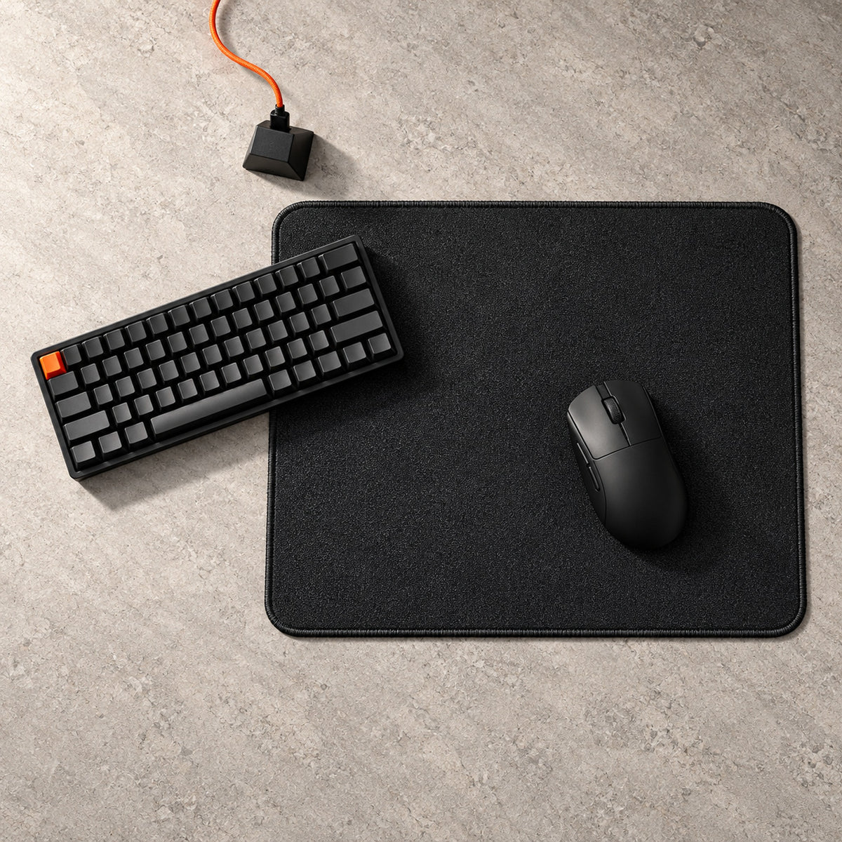 Pro Series 490 black mouse pad from above on a stone desk, with a black keyboard and gaming mouse; black stitched edge