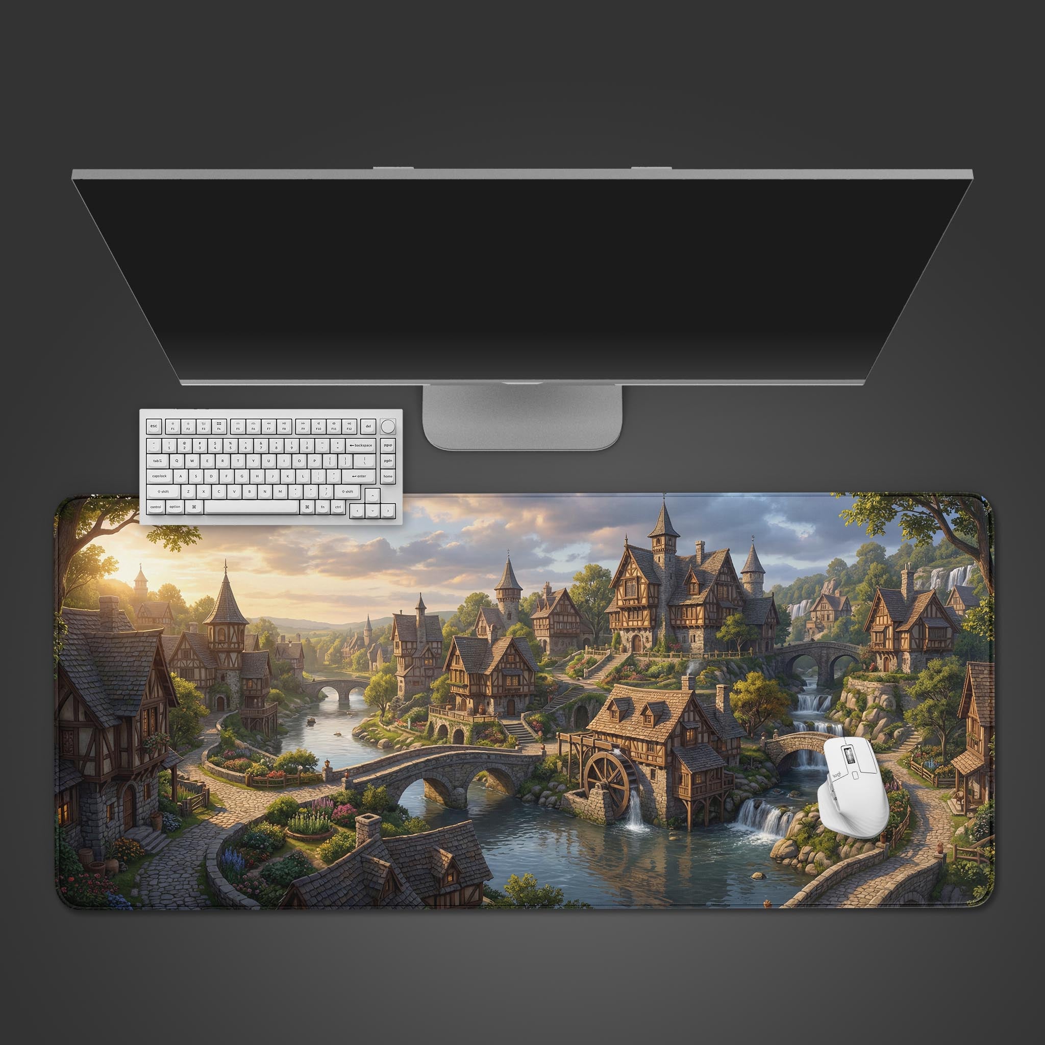 Top-down view of the Riverside Merchant gaming desk mat. A white keyboard and mouse are placed on the fantasy village artwork, below a large monitor on a clean, grey background. - Epic Design Pads & Mousepads