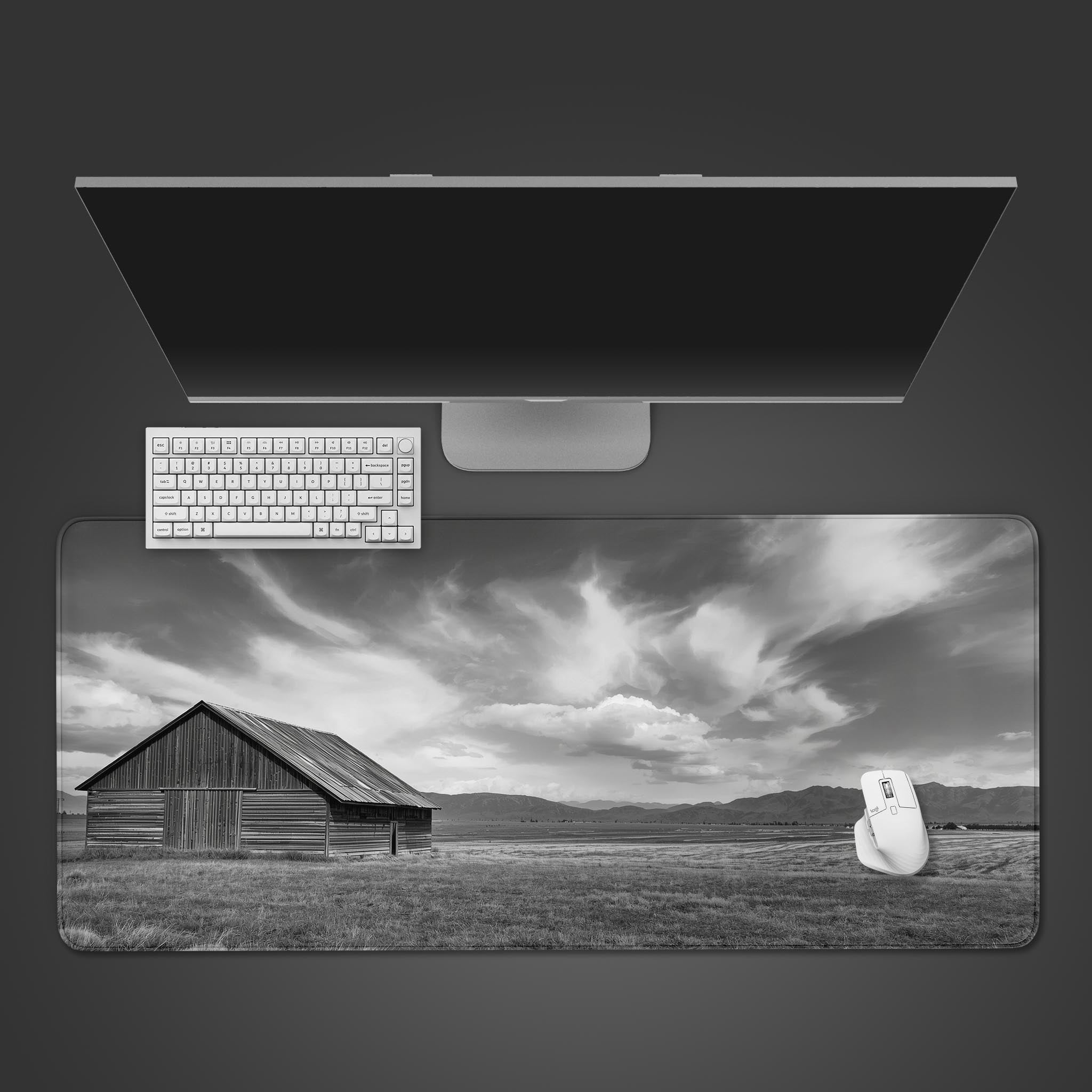 Rustic Vista desk mat with a black and white barn landscape design, shown on a clean desktop with a keyboard and mouse. - Epic Design Pads