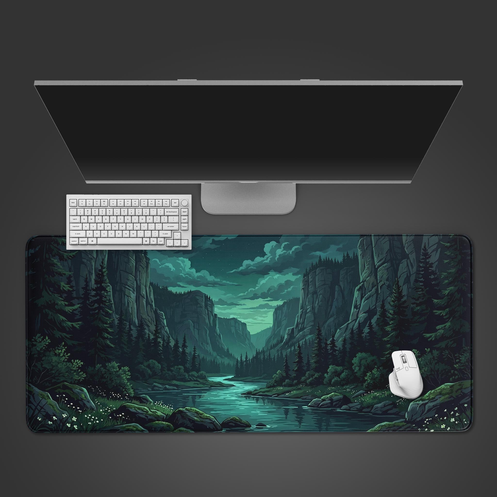 Top-down view of the Silent Gorge gaming desk mat featuring a dark forest river scene, shown with a white keyboard, mouse, and a large monitor on a clean desk setup. - Epic Design Pads & Mousepads