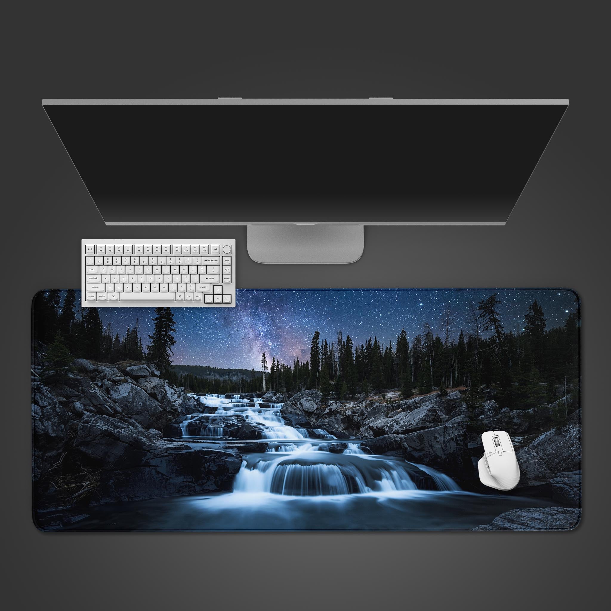 Starlight Cascade desk mat with a glowing waterfall and galaxy design, shown in a desktop view with a keyboard and mouse. - Epic Design Pads