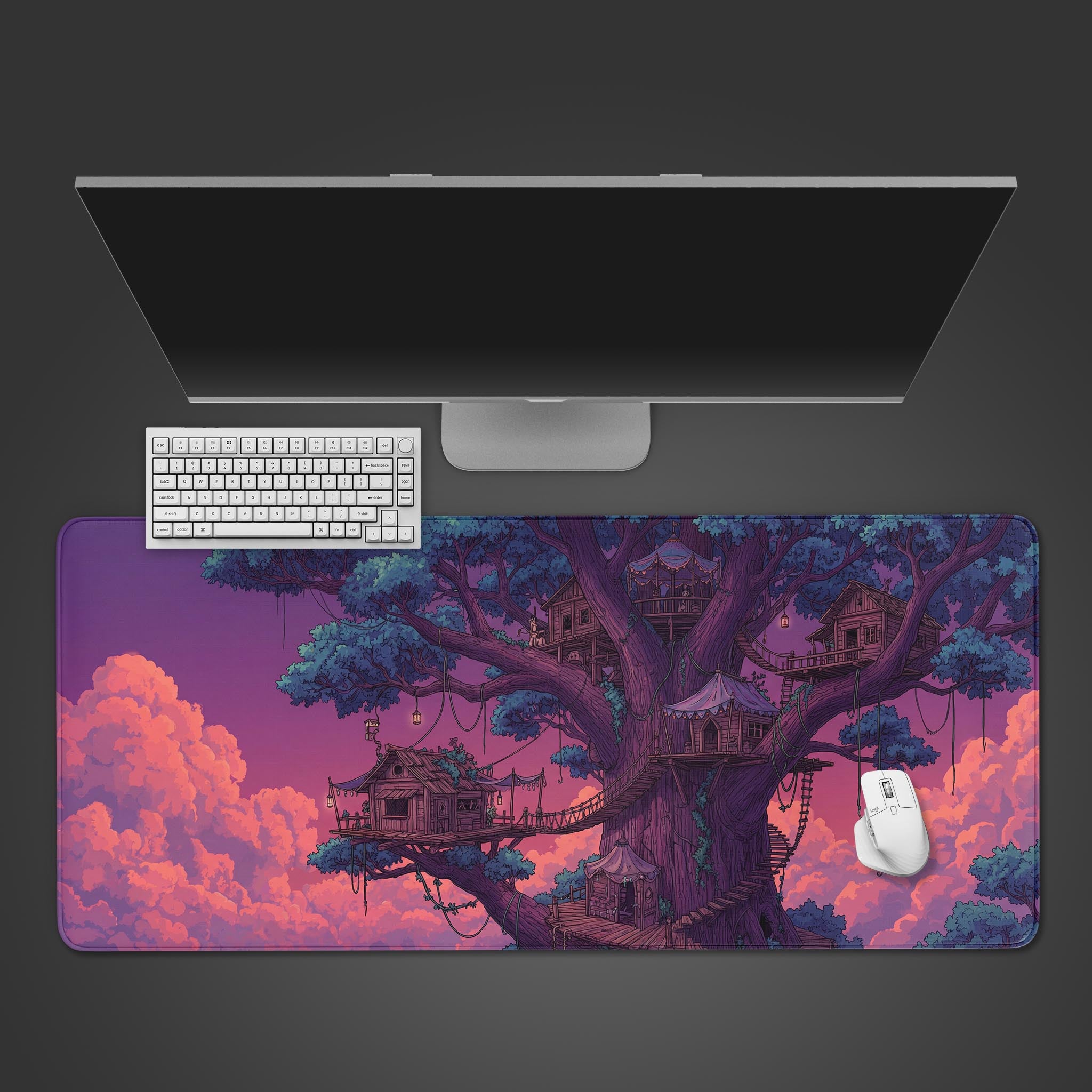 Top-down view of the Sunset Heights gaming desk mat, showcasing its fantasy treehouse art beneath a white keyboard, mouse, and a large monitor on a dark surface. - Epic Design Pads & Mousepads