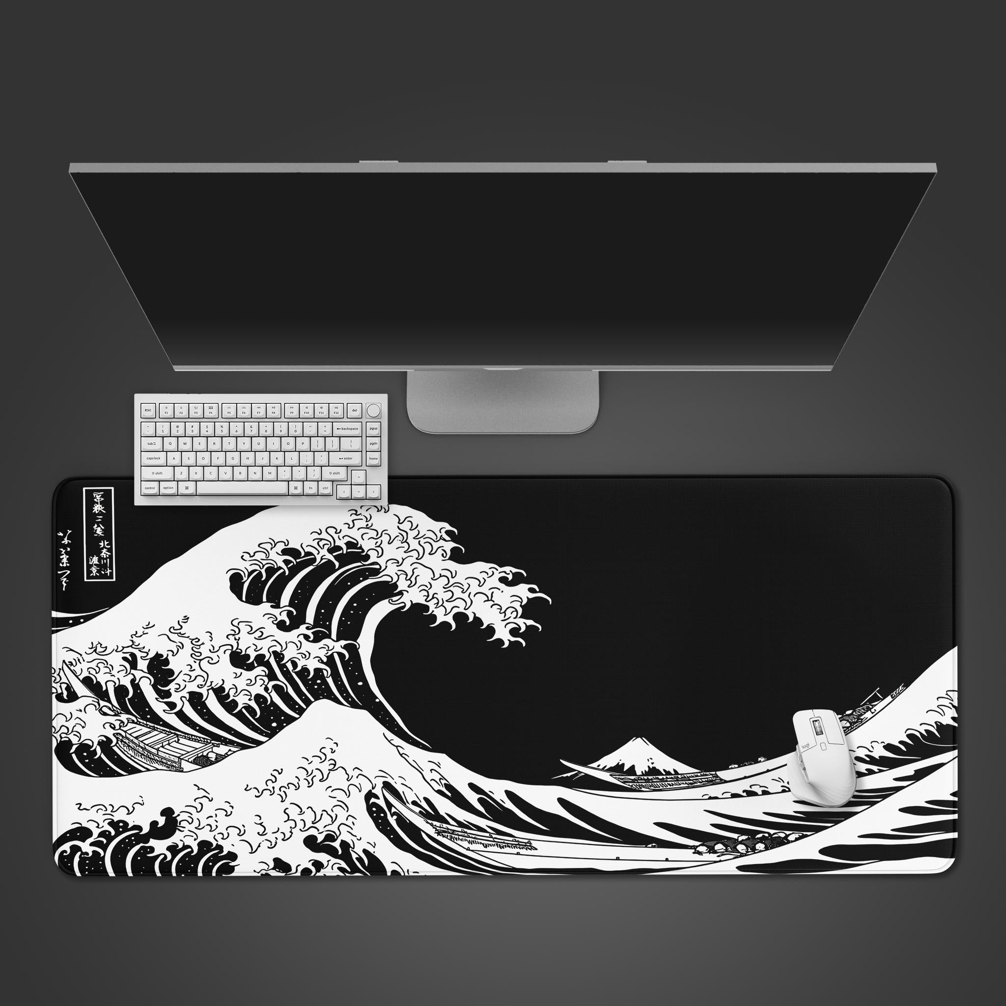 Top-down view of the black and white Great Wave Gaming Desk Mat on a dark surface, with a white keyboard, mouse, and a large monitor positioned above. - Epic Design Pads & Mousepads
