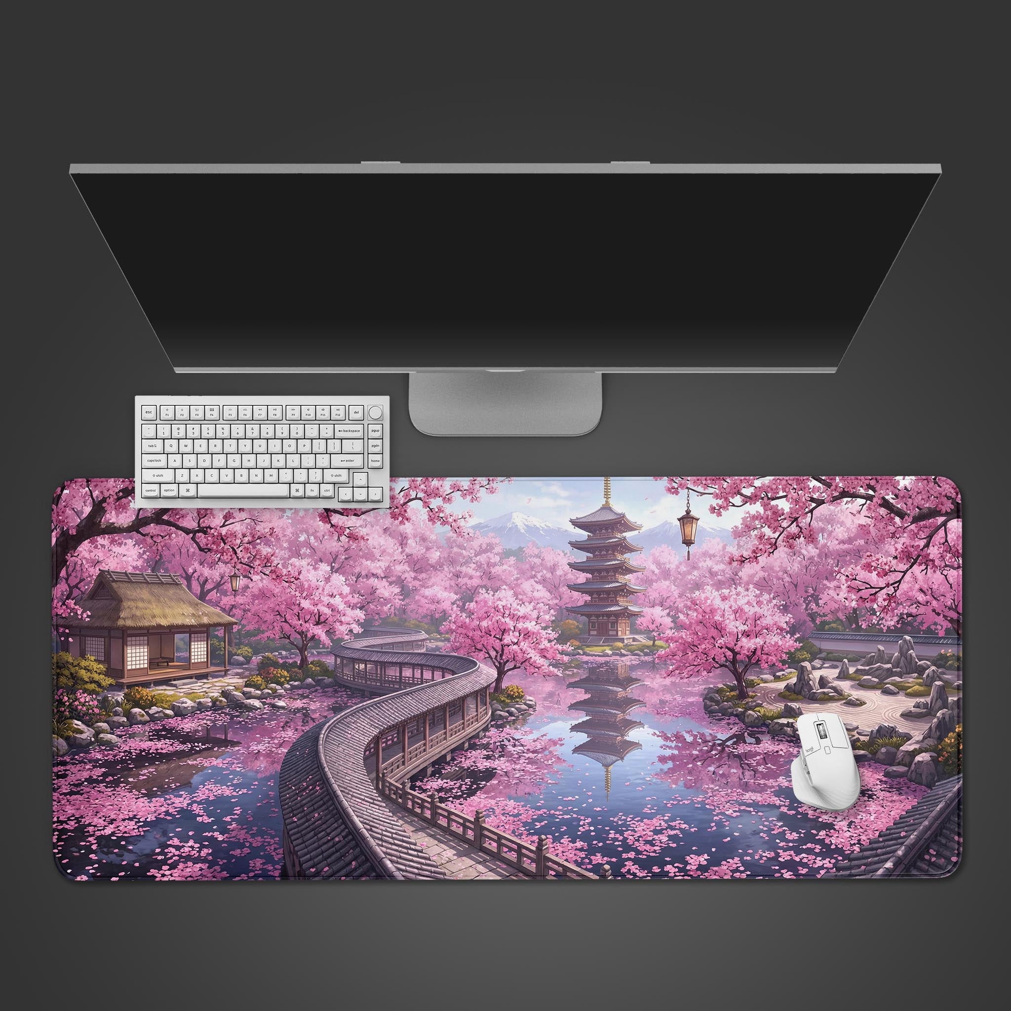 A top-down view of the Tranquil Spring gaming desk mat, featuring a Japanese garden with pink sakura trees. A white keyboard and mouse are placed on the mat below a monitor. - Epic Design Pads & Mousepads