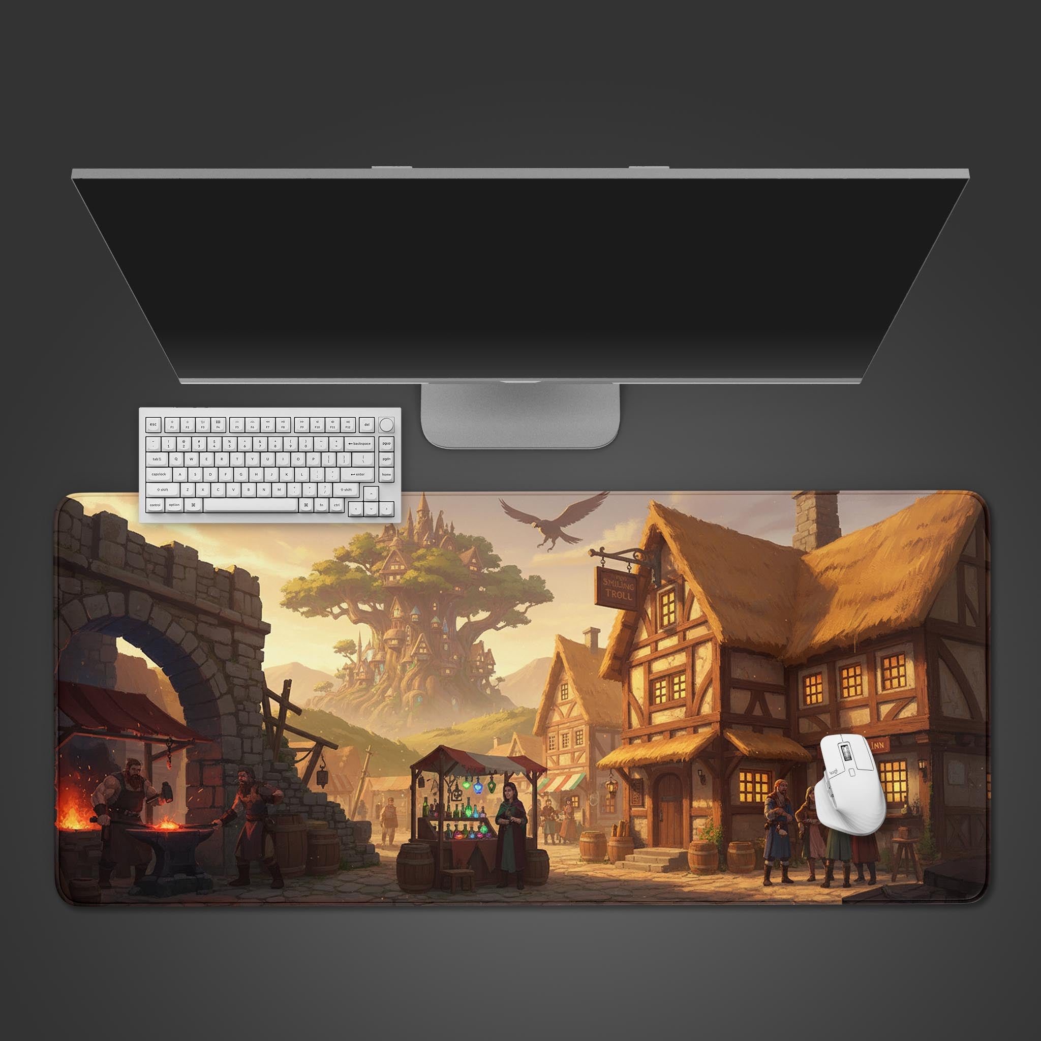 Troll's Hollow fantasy desk mat with medieval village design, shown on a desk with a keyboard and mouse. - Epic Design Pads