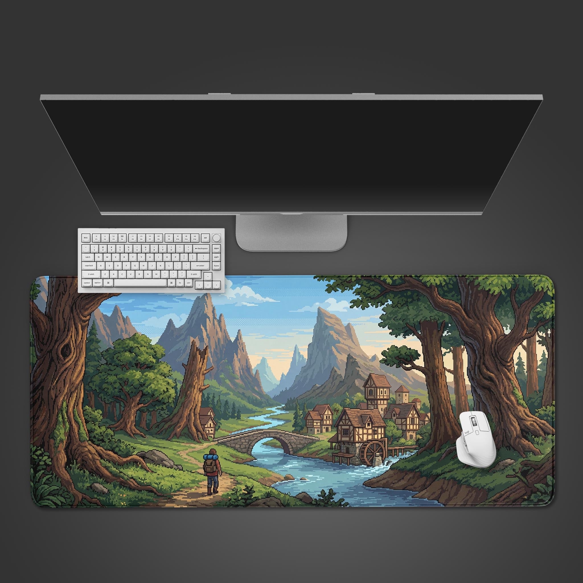 Top-down view of the Valley Hamlet gaming desk mat, featuring a pixel art landscape. A white keyboard and mouse are shown on the mat below a sleek monitor. - Epic Design Pads & Mousepads