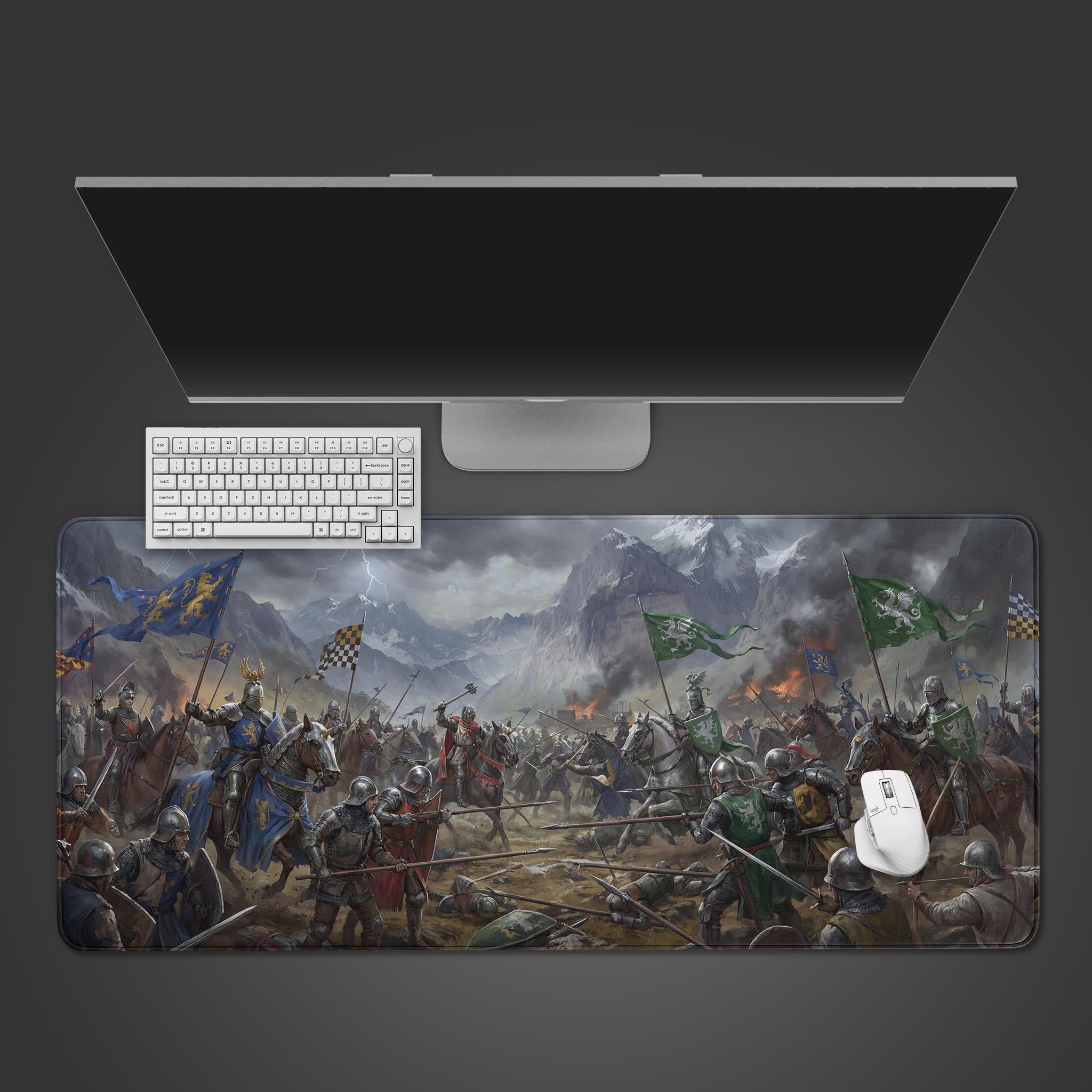 A top-down view of the Vanguard Clash Gaming Desk Mat, featuring a medieval battle scene, with a white keyboard and mouse placed on it below a computer monitor. - Epic Design Pads & Mousepads