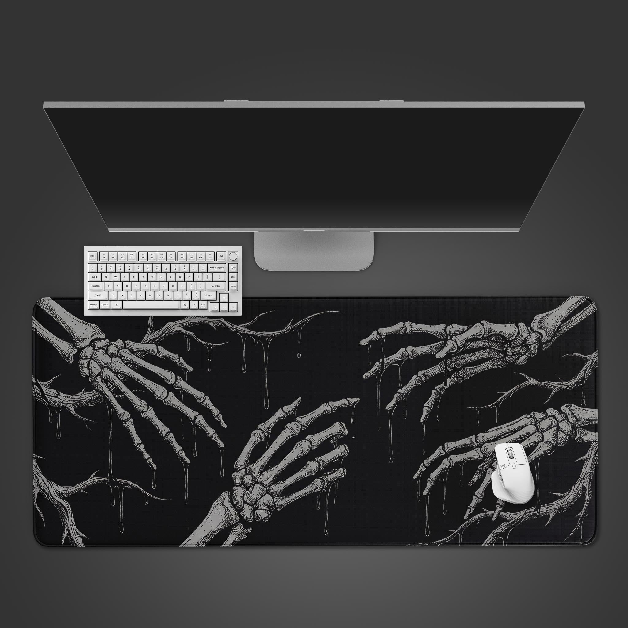 Top-down view of the Void Touch gaming desk mat with its stark skeleton hand design, shown with a white keyboard, mouse, and a monitor on a dark surface. - Epic Design Pads & Mousepads