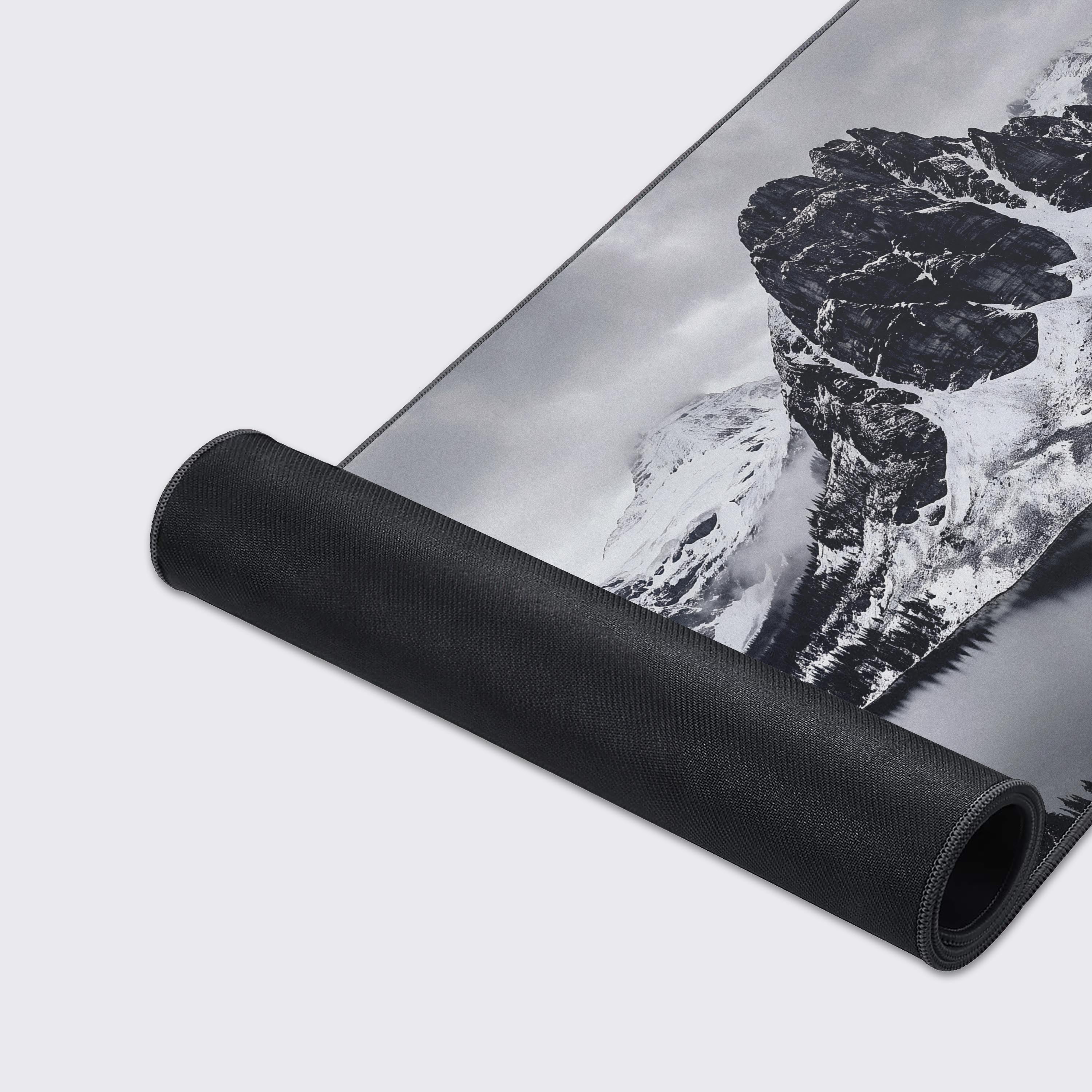 A sleek desk mat featuring a monochromatic landscape with a dramatic mountain range under overcast skies.