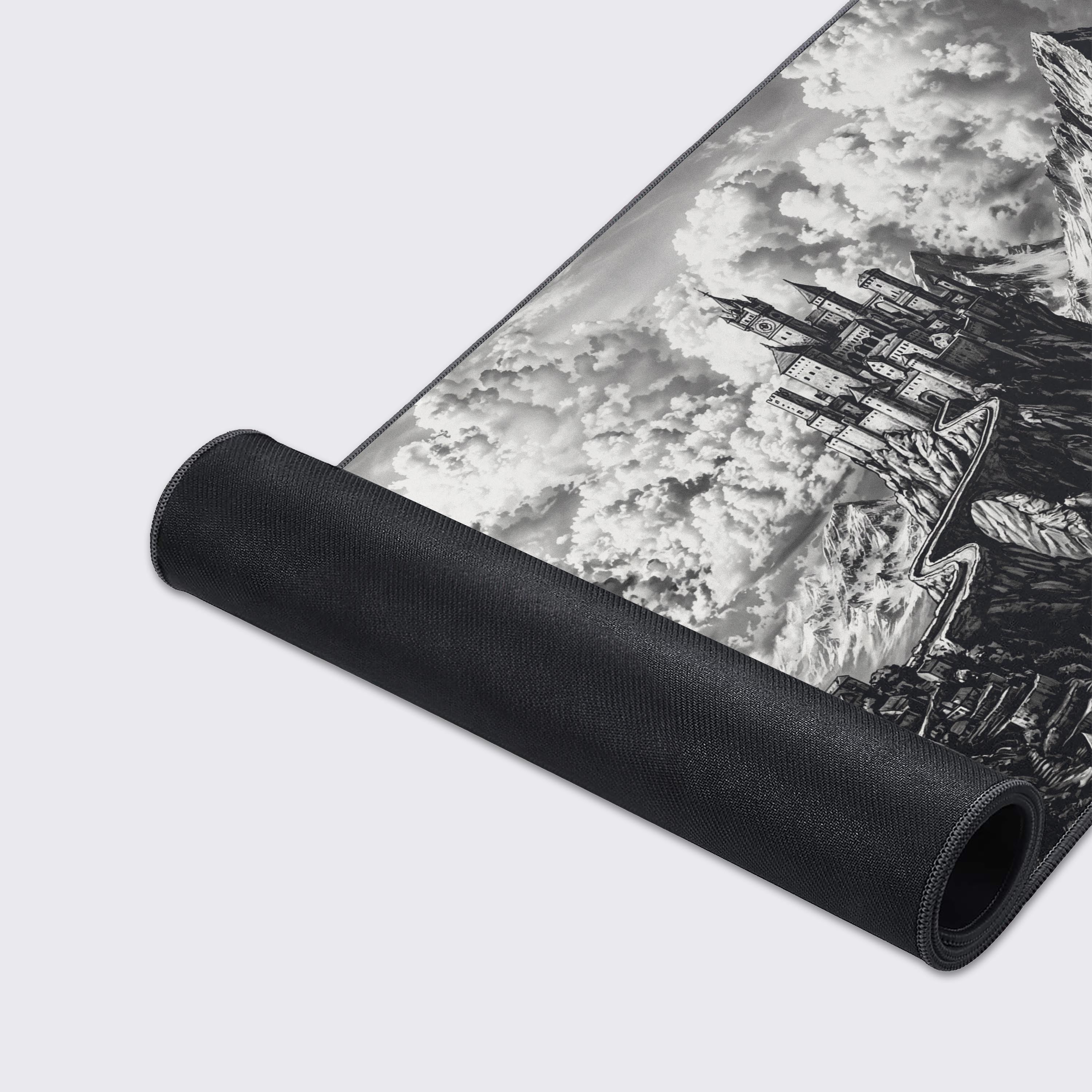 Close-up of the smooth fabric and stitched edges on 'The High Keep' gaming desk mat, highlighting the detailed black and white illustration of the mountain fortress. - Epic Design Pads & Mousepads