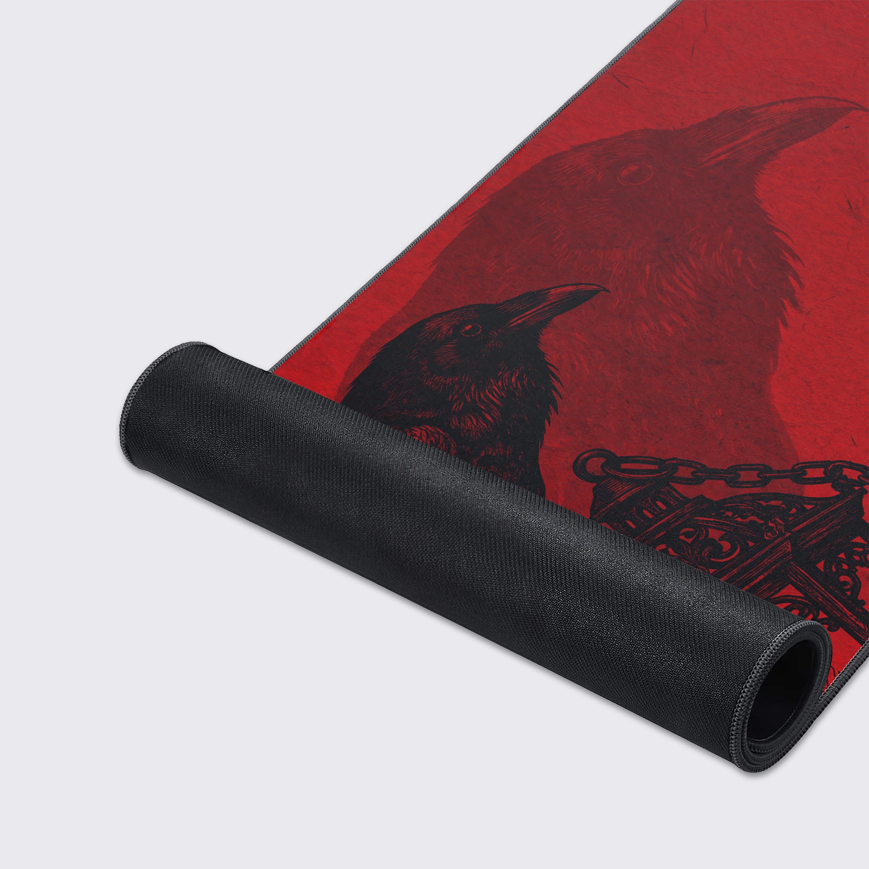Close-up of the Crimson Raven gaming desk mat, highlighting the high-quality fabric texture, stitched edges, and the detailed black raven artwork on the red surface. - Epic Design Pads & Mousepads