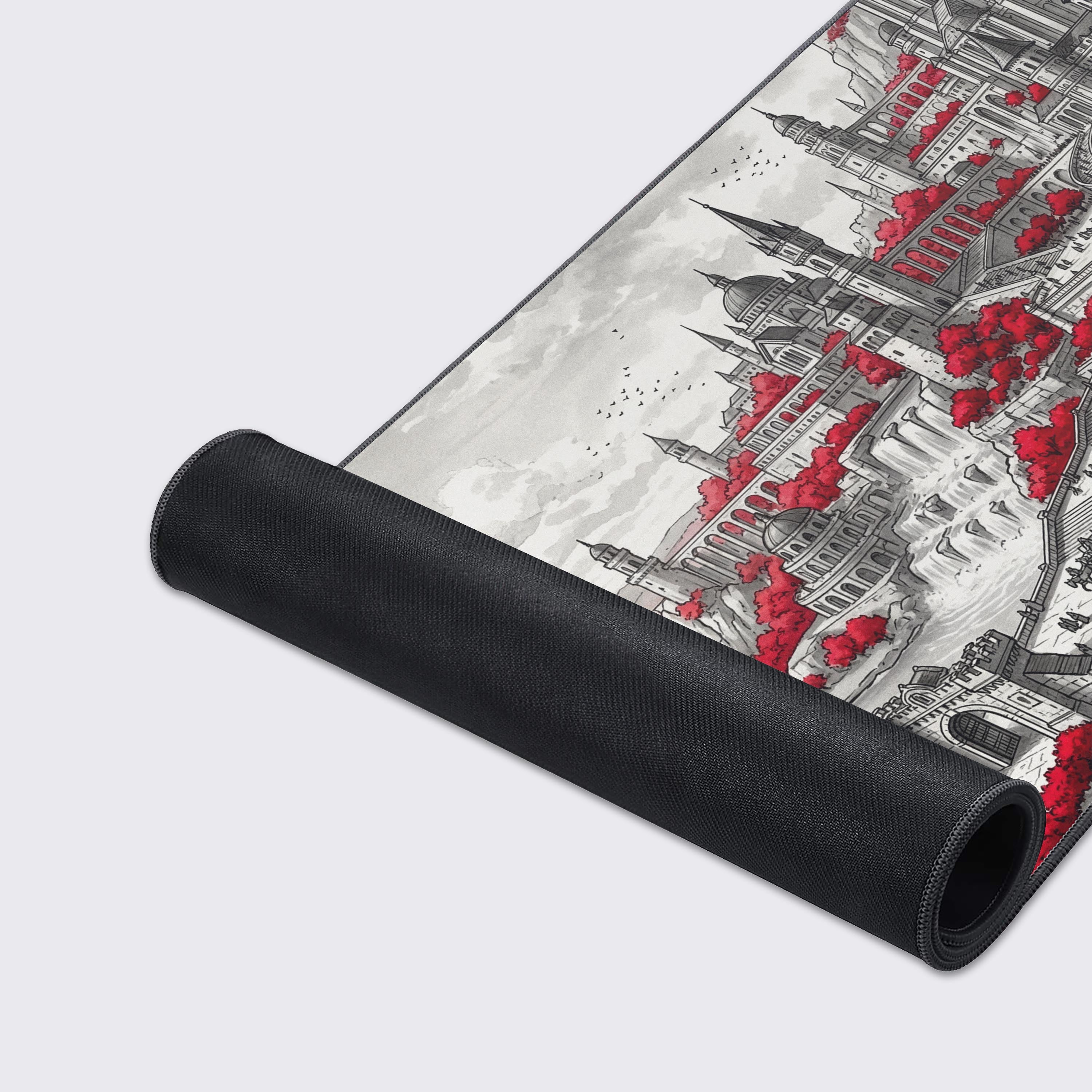 A close-up of the Redwater Realm gaming desk mat showcases its smooth texture and stitched edges, detailing the red and black castle illustration. - Epic Design Pads & Mousepads