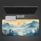 This desk mat features a serene mountain landscape with a gradient of blue and orange hues, depicting a sunrise or sunset. The design includes rolling mist over the mountains, vibrant autumnal trees in the foreground, and birds flying across the sky, creating a calming, nature-inspired aesthetic. Its soft color palette and intricate details make it visually appealing and perfect for adding a tranquil vibe to any workspace.