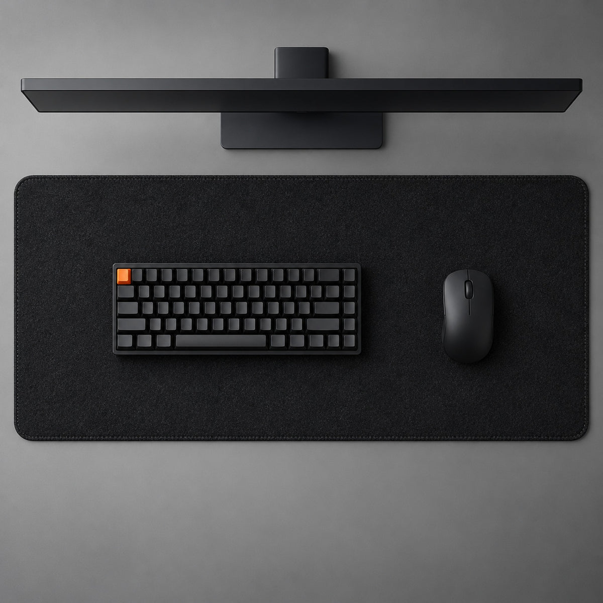 Black felt desk pad, 90 x 40 cm, seen from above with a black keyboard, mouse and monitor