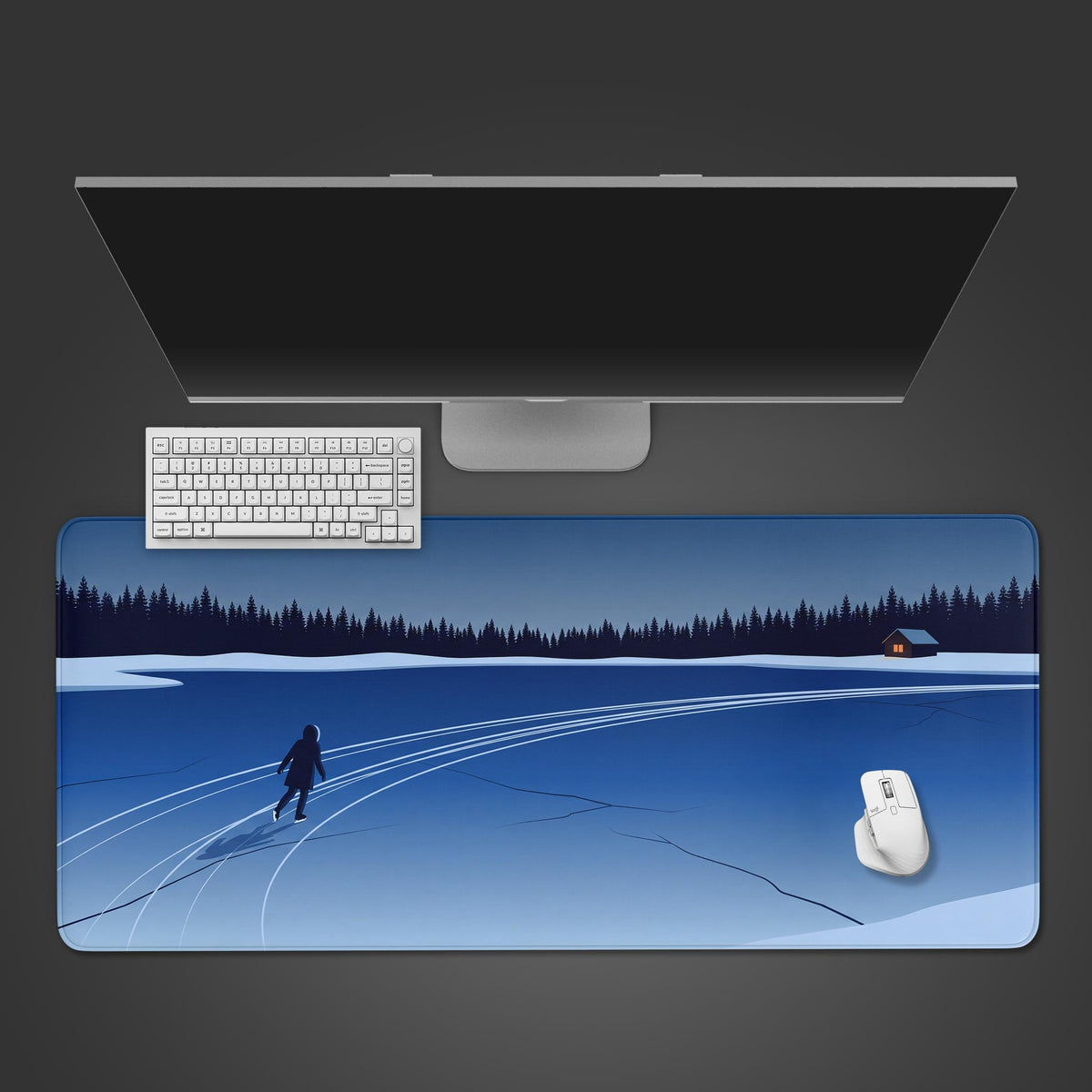 Blue frozen lake minimalist desk mat seen from above, ice skater and pine forest, with a white keyboard, mouse and monitor