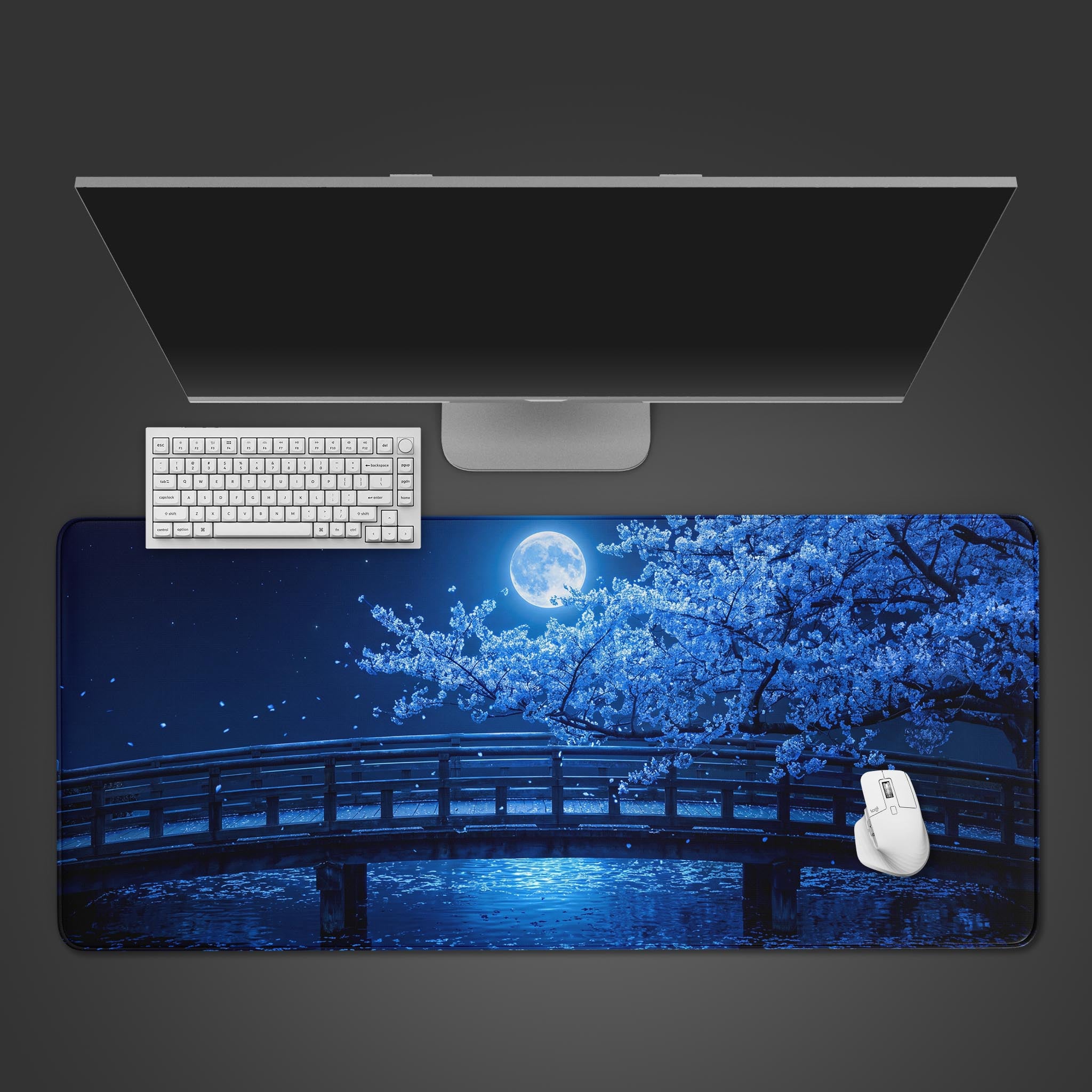 A rectangular desk mat displaying a night scene with a wooden bridge, glowing blue cherry blossoms, a full moon, and water reflections.