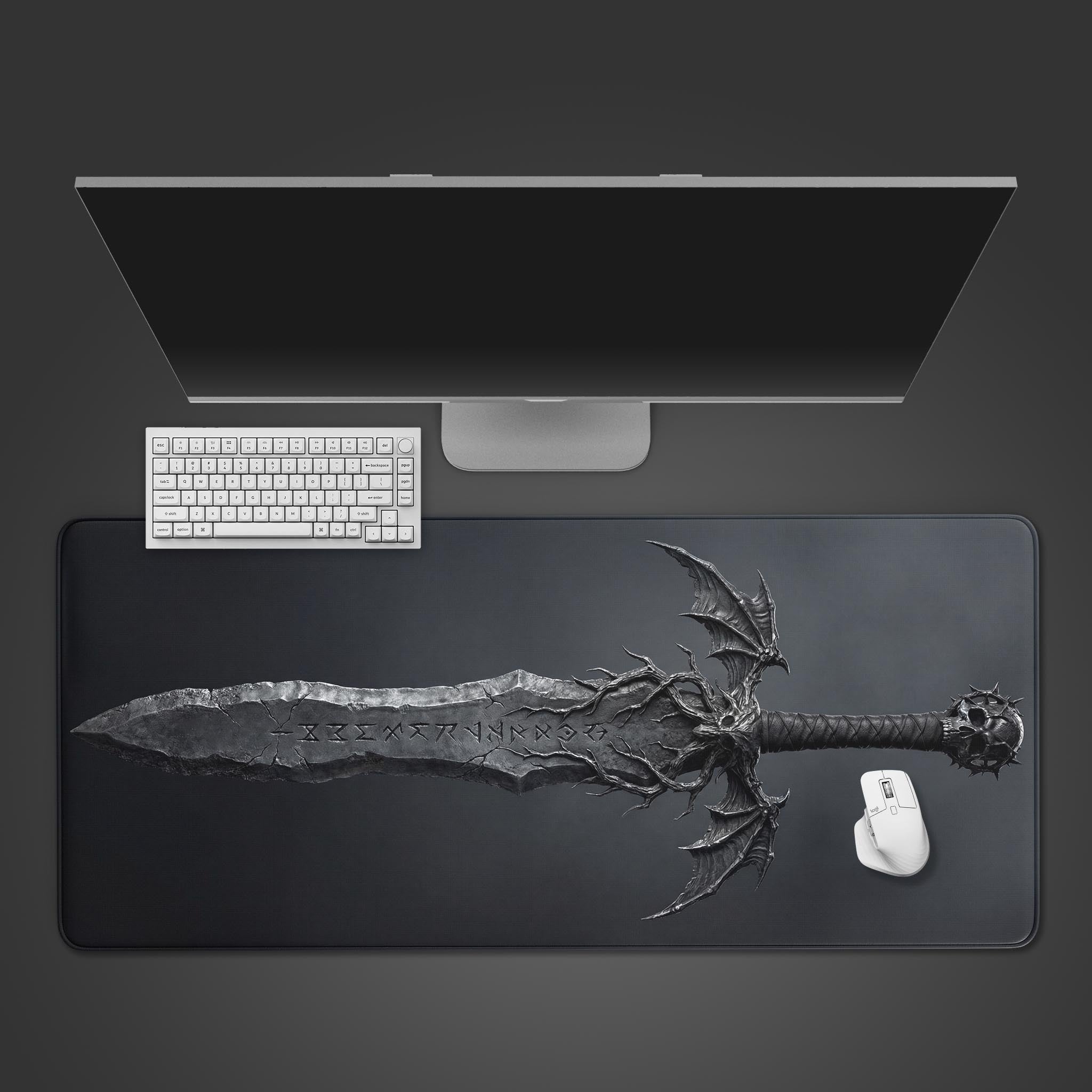 Top-down view of the Cursed Steel gaming desk mat featuring a dark fantasy greatsword, shown with a white keyboard, mouse, and a monitor on a grey desk. - Epic Design Pads & Mousepads