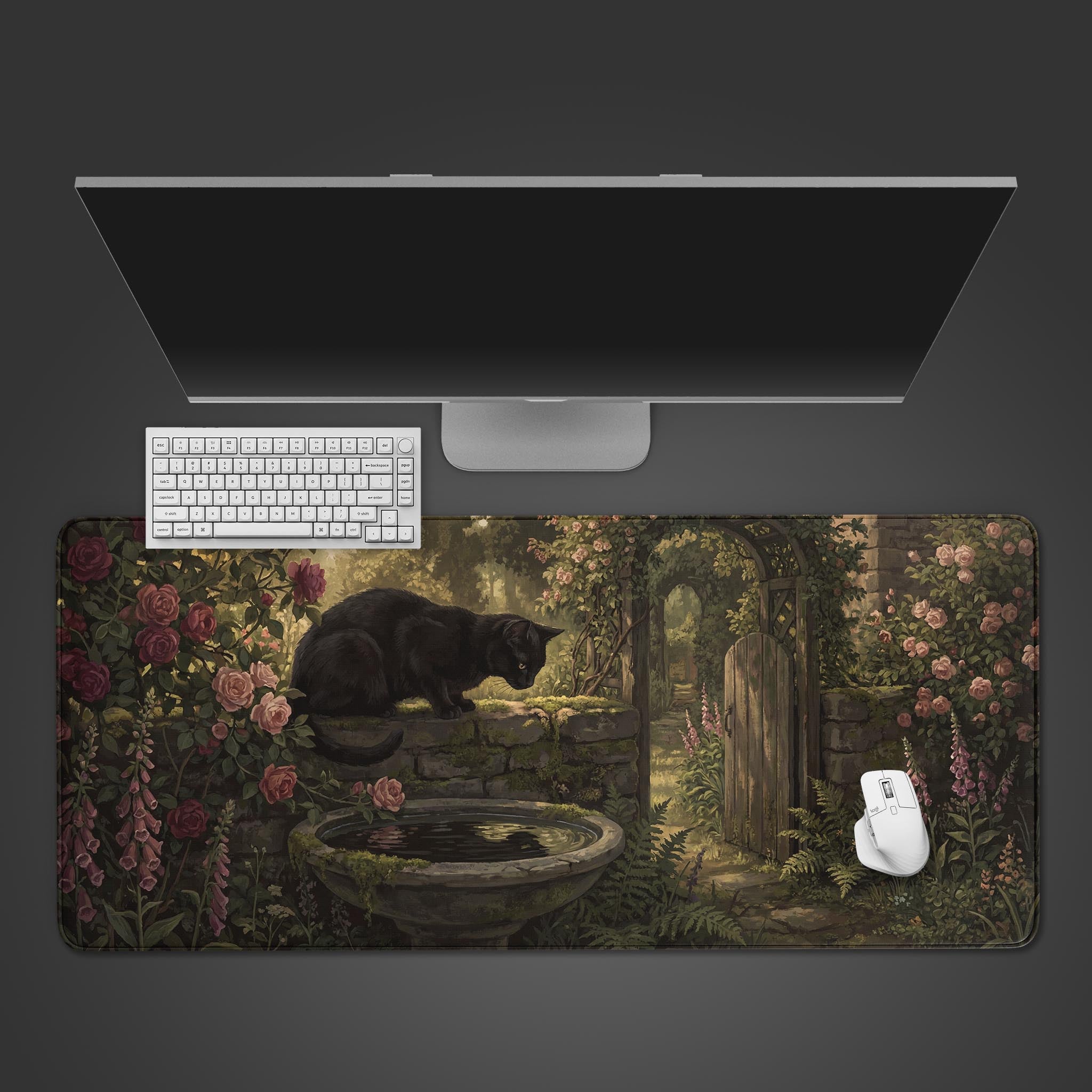 Top-down view of the Garden Watcher gaming desk mat, featuring a black cat in a rose garden, shown with a white keyboard and mouse on a dark surface. - Epic Design Pads & Mousepads