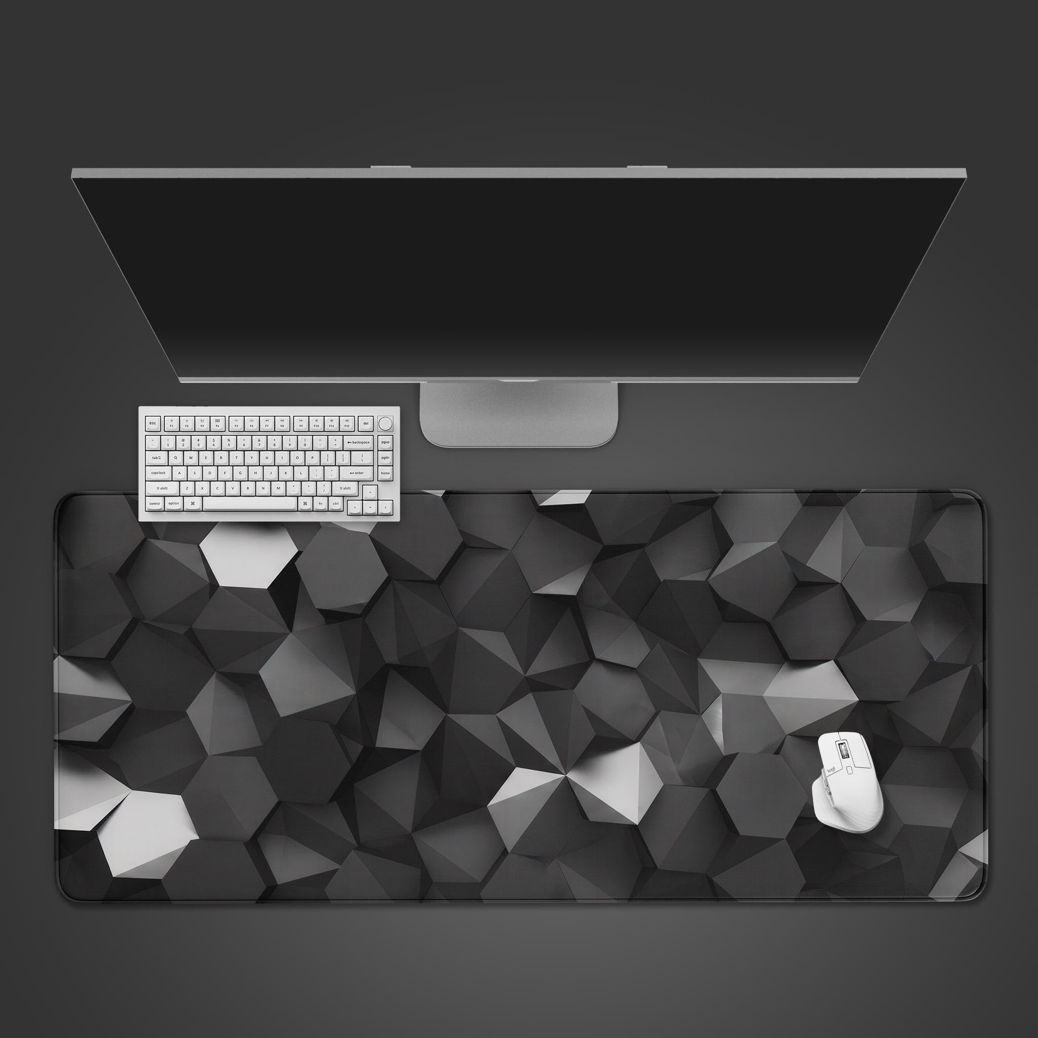 A large gaming desk mat featuring a dark, 3D geometric polygon design in shades of black and gray.