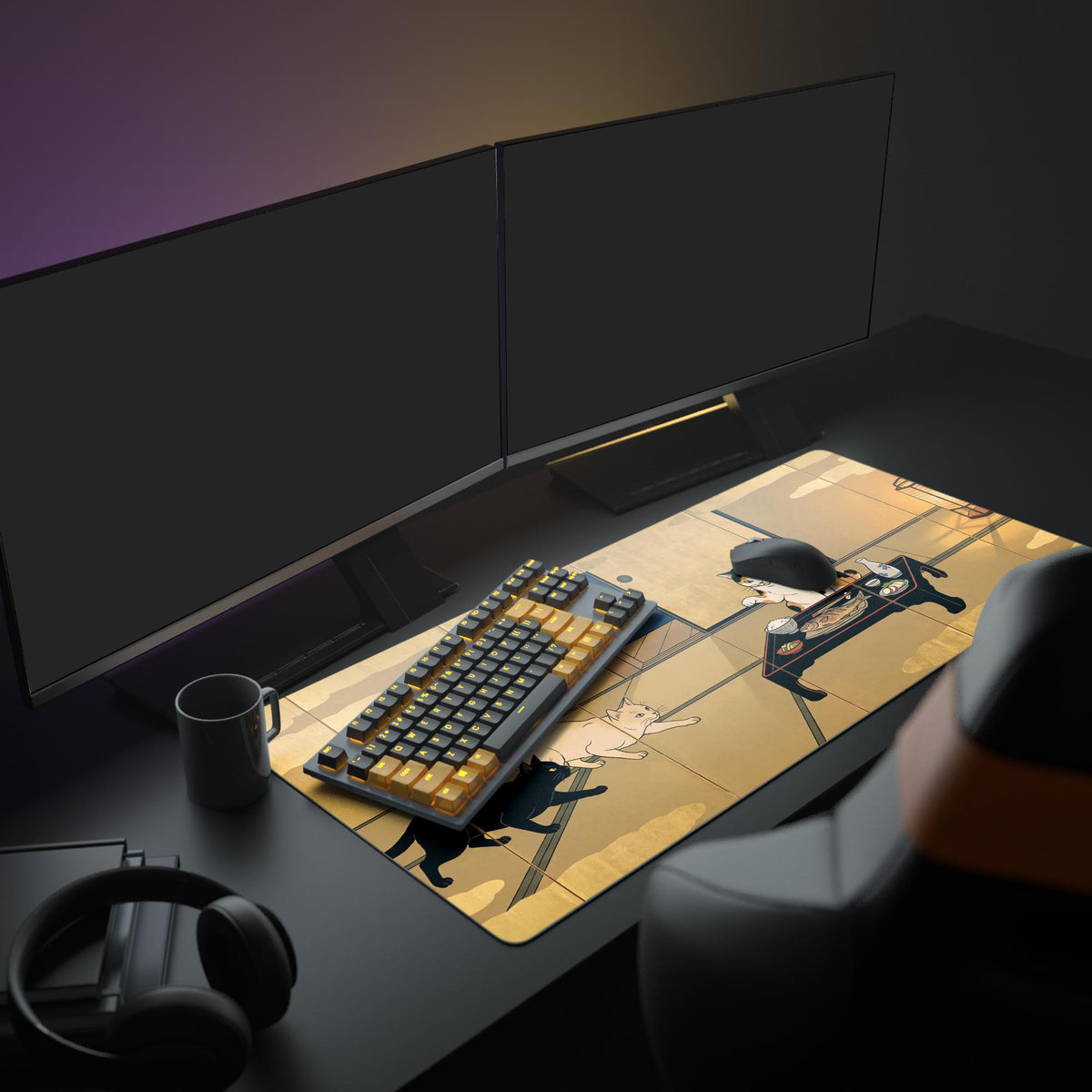 Desk mat on a dark desk with two monitors, keyboard, mug and headphones; black and cream cats creep toward a calico's meal