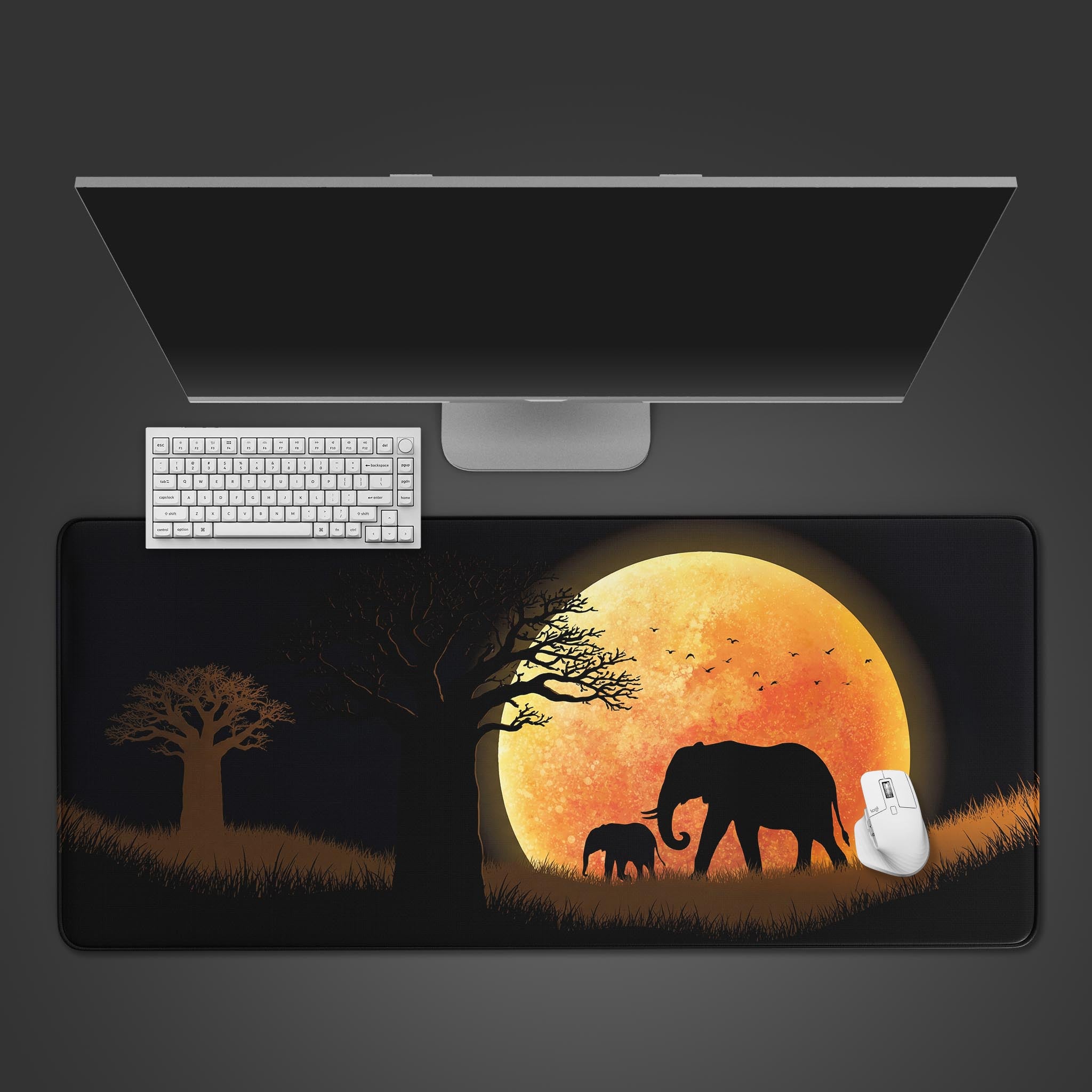 Top-down view of the Golden March gaming desk mat, featuring elephant silhouettes against a golden moon, shown with a white keyboard and mouse. - Epic Design Pads & Mousepads