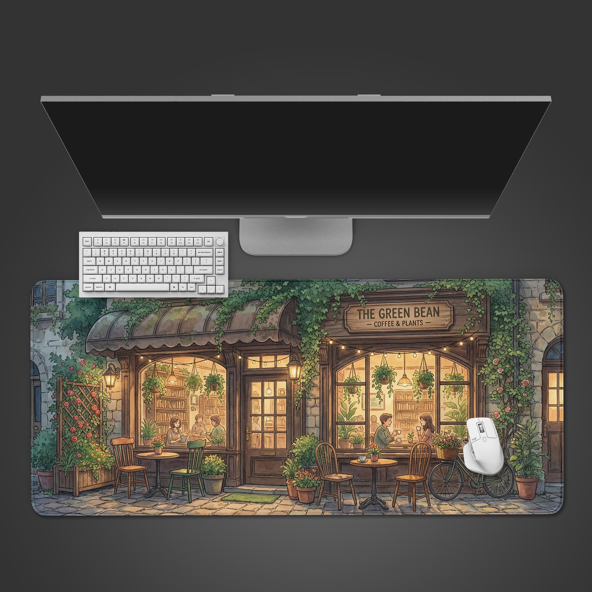 A top-down view of the Green Bean Cafe gaming desk mat, showcasing the cozy coffee shop illustration alongside a sleek white keyboard, mouse, and a large monitor. - Epic Design Pads & Mousepads