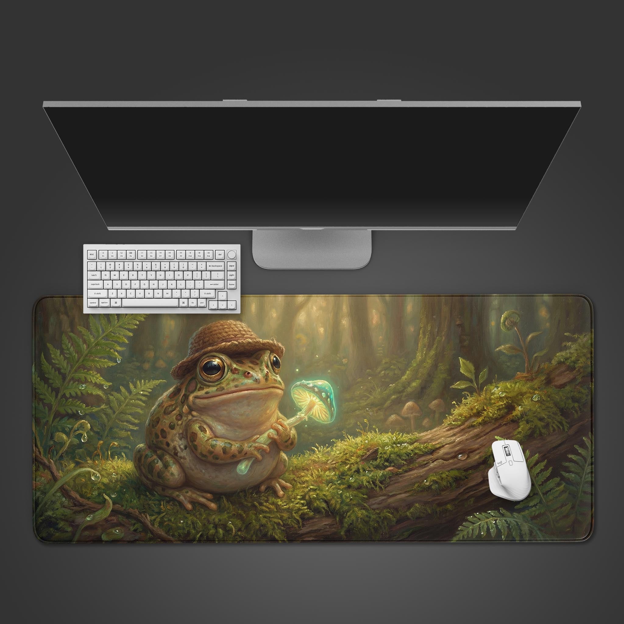 Top-down view of the Luminous Warden frog gaming desk mat, shown with a white keyboard, mouse, and a large monitor on a dark background. - Epic Design Pads & Mousepads