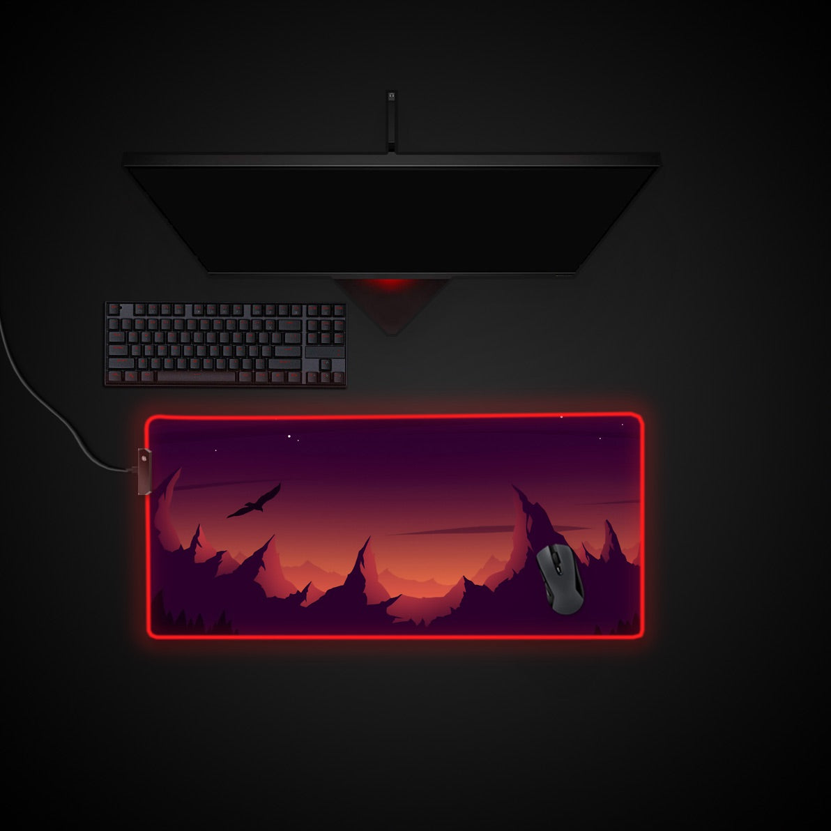 Gaming setup with a monitor, keyboard, and mouse pad on a dark background