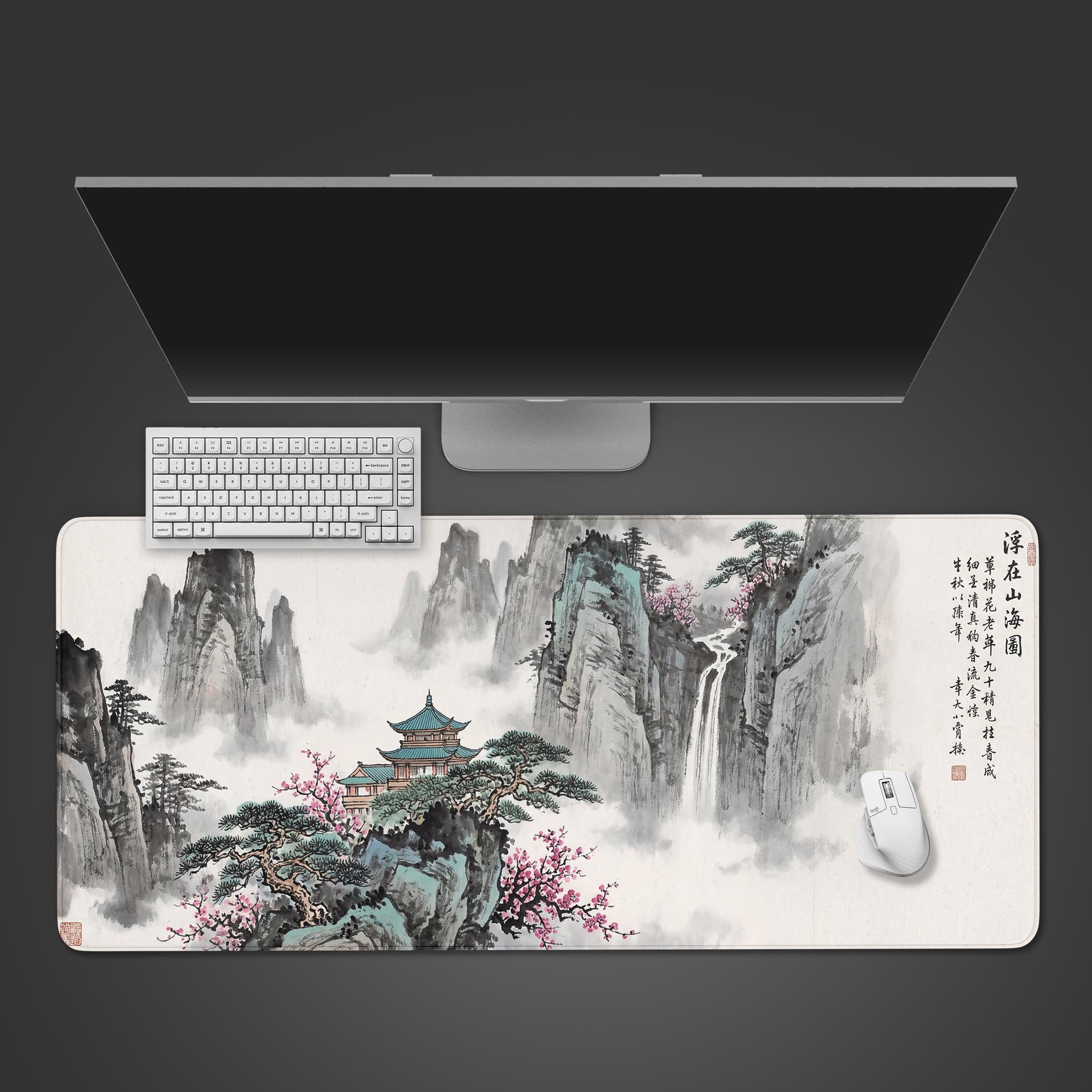 Top-down view of the Misty Pavilion gaming desk mat, featuring a Chinese ink wash mountain landscape, with a white keyboard and mouse on top under a monitor. - Epic Design Pads & Mousepads